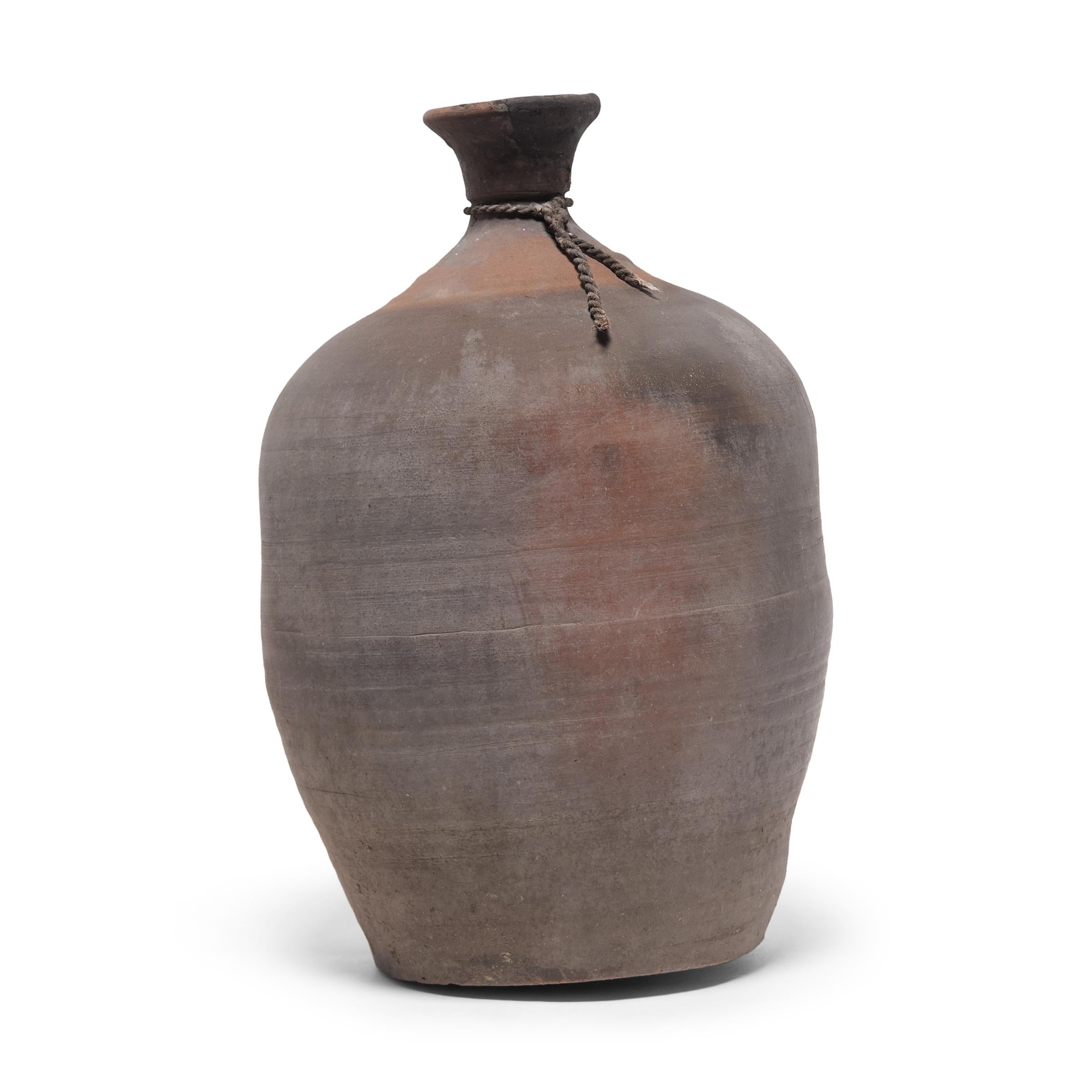 These early 20th century ceramic jars from China's Shandong province were formed with a bottle-neck shape meant for storing vinegar or rice wine. We suspect these jars were created to store wine for commercial sale, and were likely stoppered with a