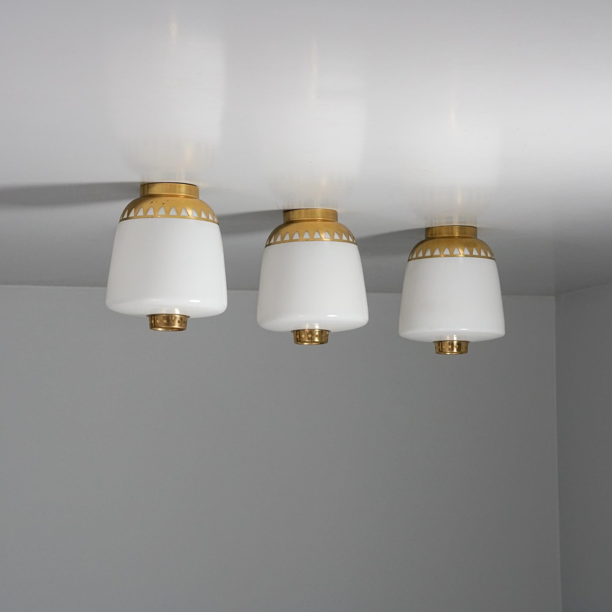 Set of three rare flush mounts, designed by Lisa Johansson-Pape, manufactured by Orno Oy, 1940/1950s. Milk glass and brass. Good vintage condition, minor patina consistent with age and use. The flush mounts are sold together as a set. 