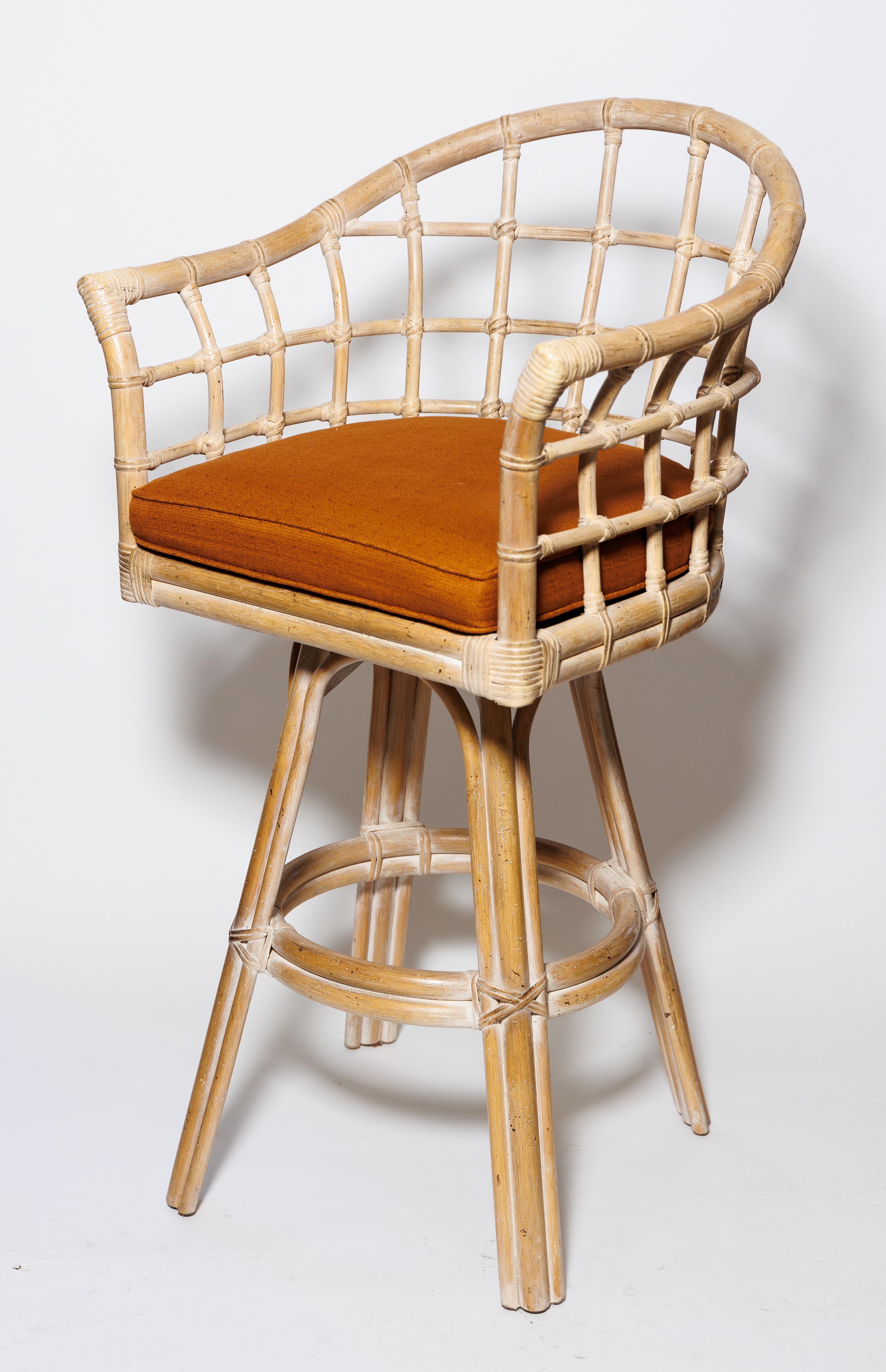 A set of three upholstered swivel woven rattan bar stools.