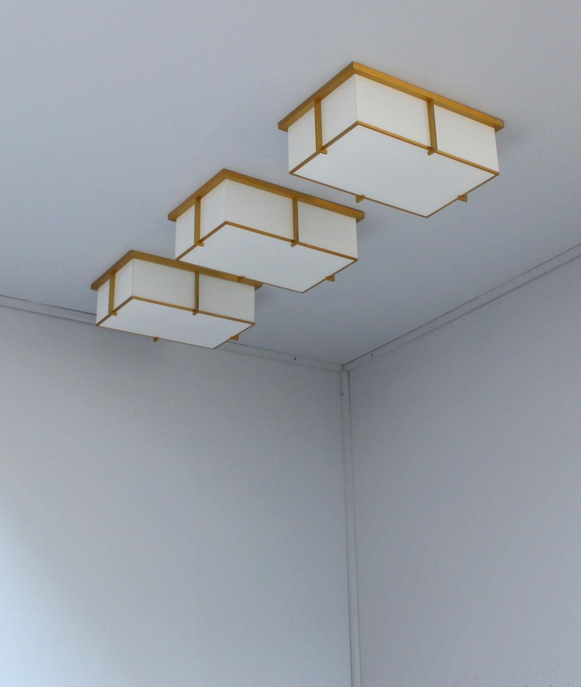 Mounted on a gold lacquered bronze frame that holds the white laminated glass diffusers. The flat square horizontal diffuser is easily removable in order to change the bulbs.