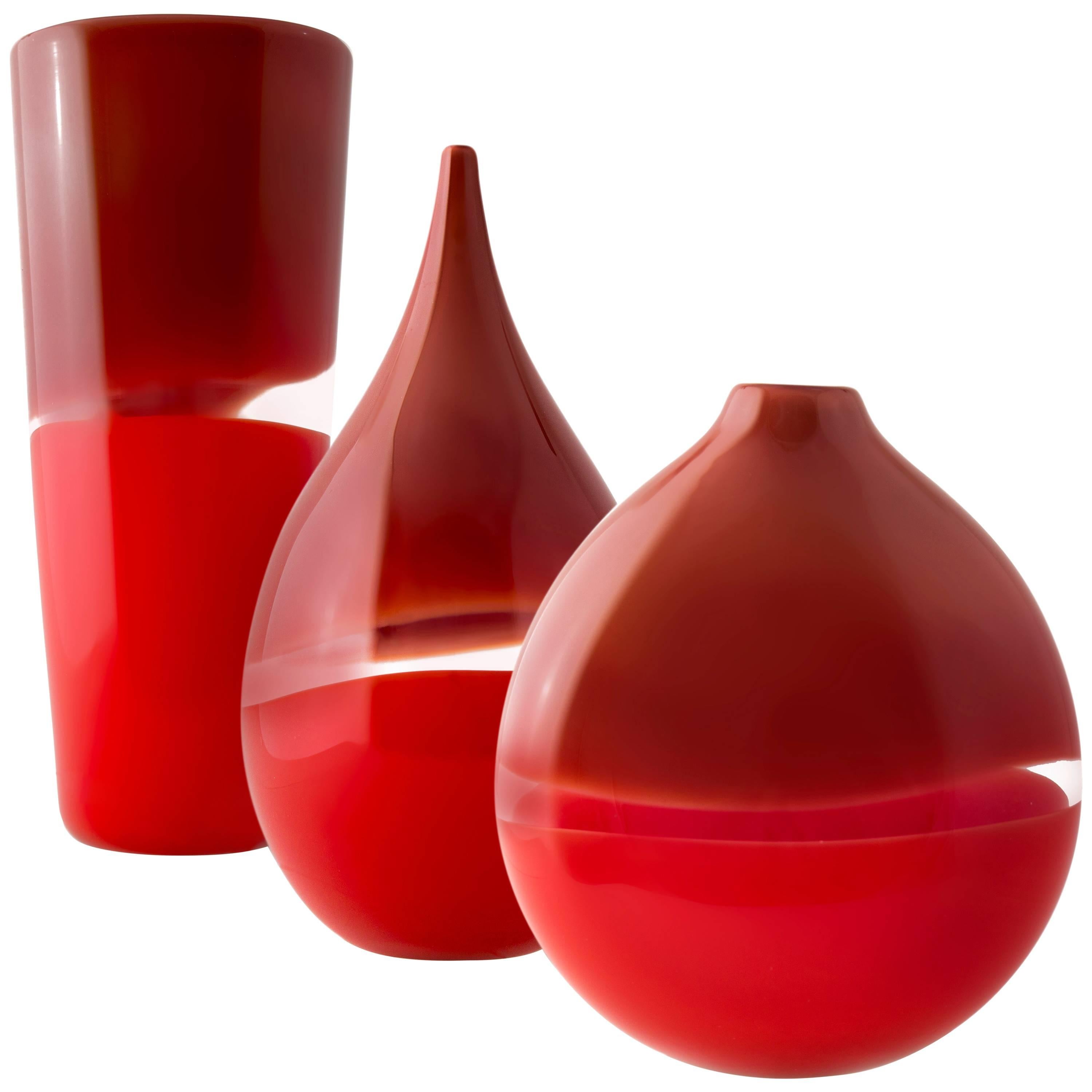 Red two-tone series, cylinder, flat round, and teardrop vases
Scandinavian Modern red blown glass vase. These striking pieces draw inspiration from the rich hues and undulating topography of Southern California. Alternating layers of opaque and