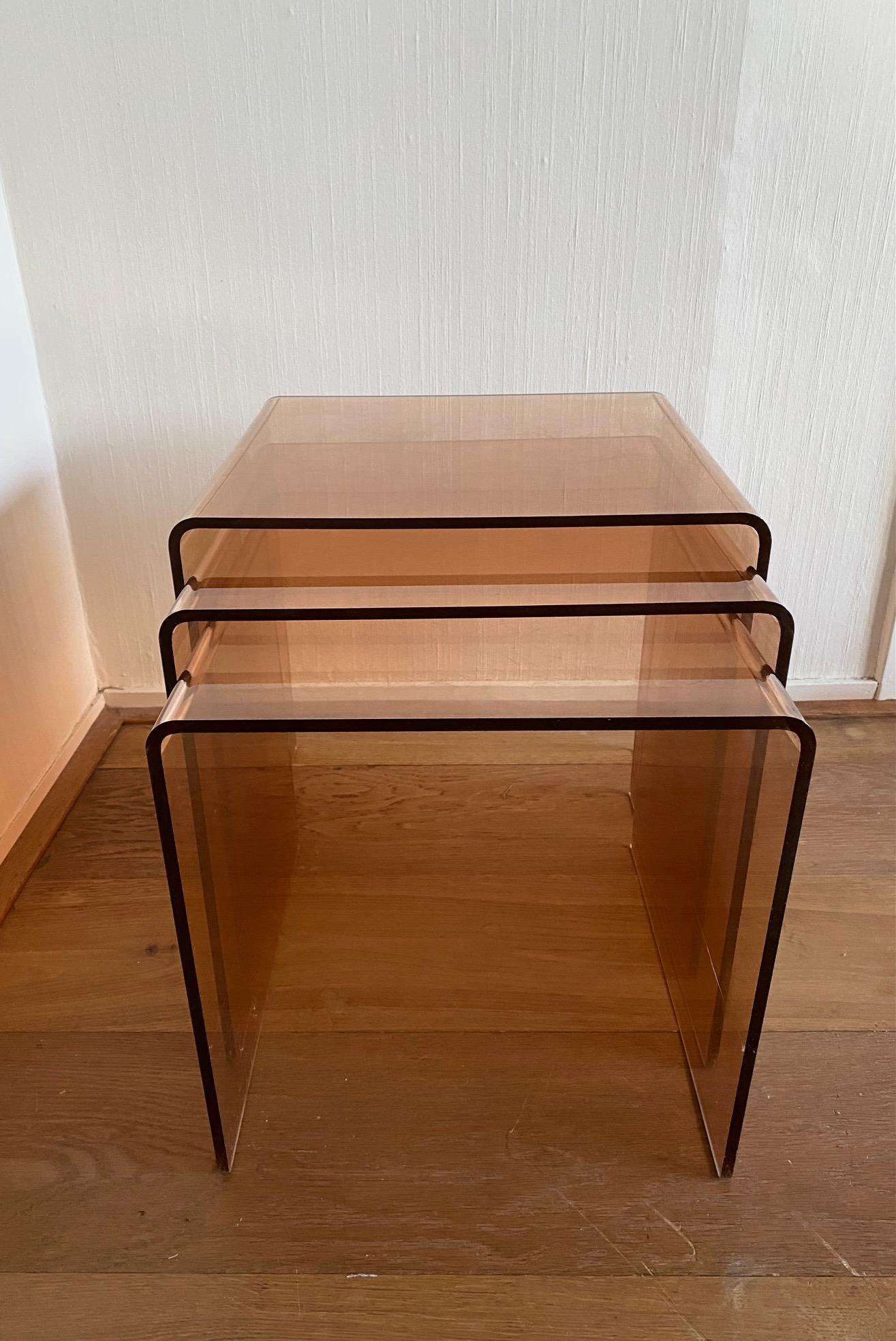 Set of three Lucite nesting tables. Smoked Rosé/Orange color. Manufactured ca. in the 1970s in France and in similar to the pieces of Michel Dumas. The tables show overall cosmetic wear as scratches. No structural issues.

Large height:41 cm width