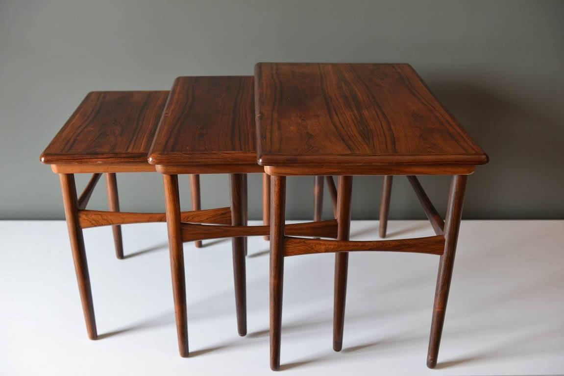 Set of three rosewood nesting tables by Poul Hundevad, circa 1960. Stylish compact form and slender conical legs. Designed with glide rails on the underside for easy removal or storage of each table. Very good condition with only slight wear on