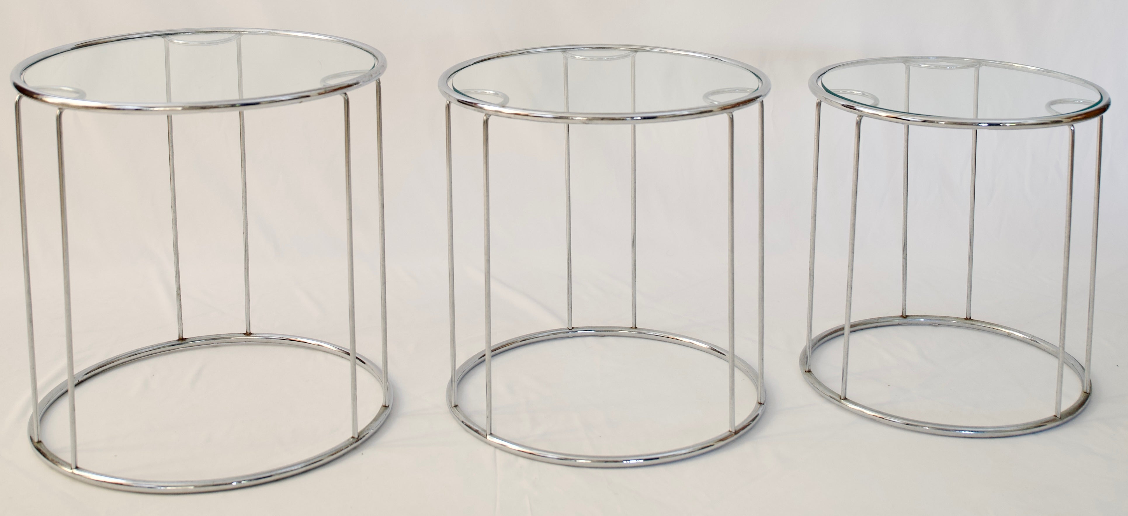 A vintage set of three, round cylindrical nesting tables, with chrome and glass tops, designed by Milo Baughman, circa 1960s. 

These highly functional end or side tables can be separated and used in living room, a bedroom, or home office. Wonderful