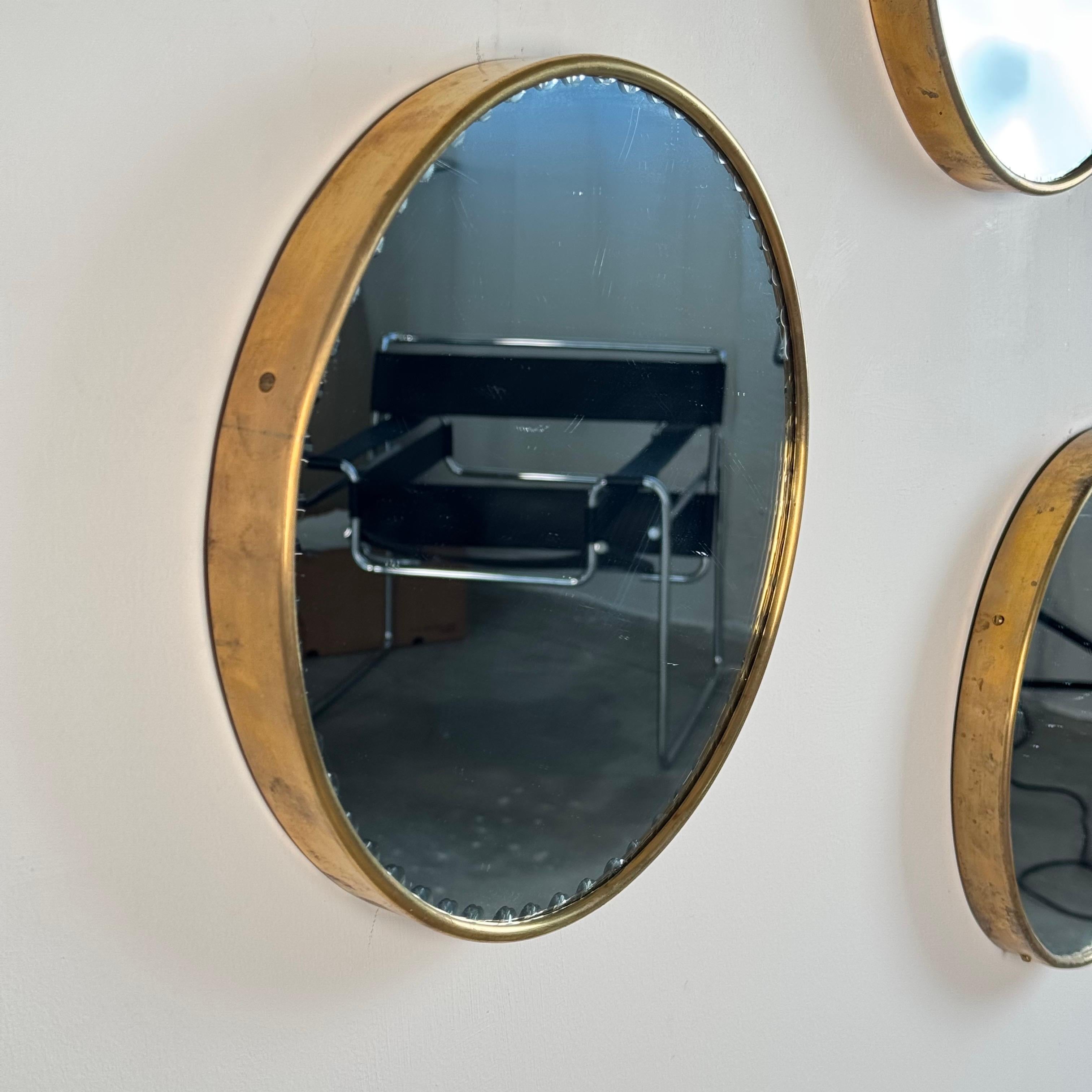 Un raffinato set di tre specchi da parete rotondi prodotti da Cristal Arte in Italia negli anni Settanta. Ogni specchio è caratterizzato da una sottile cornice in ottone con un vetro a specchio morbidamente smussato, che mette in mostra l'elegante