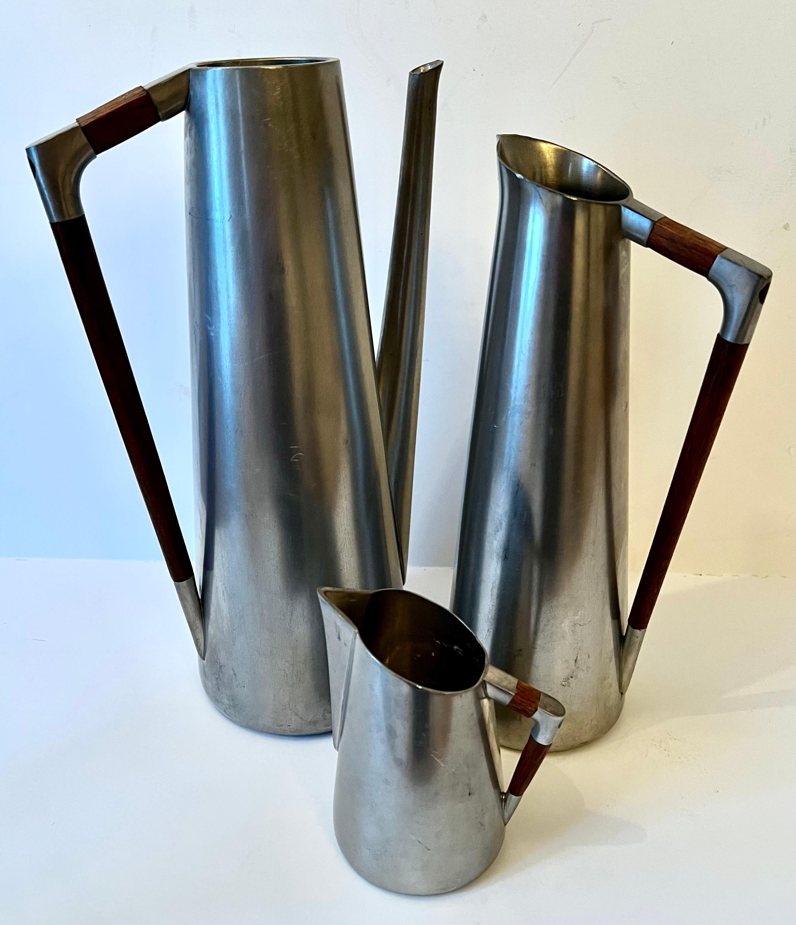 Set of Three Pewter and Teak Pitchers. The measurements for the large pitcher are in the description.  The medium sized is 4x3x10, smaller is 3.5x4.5x2.5

This mid-century set is a compliment to many settings and is the ultimate danish mid century