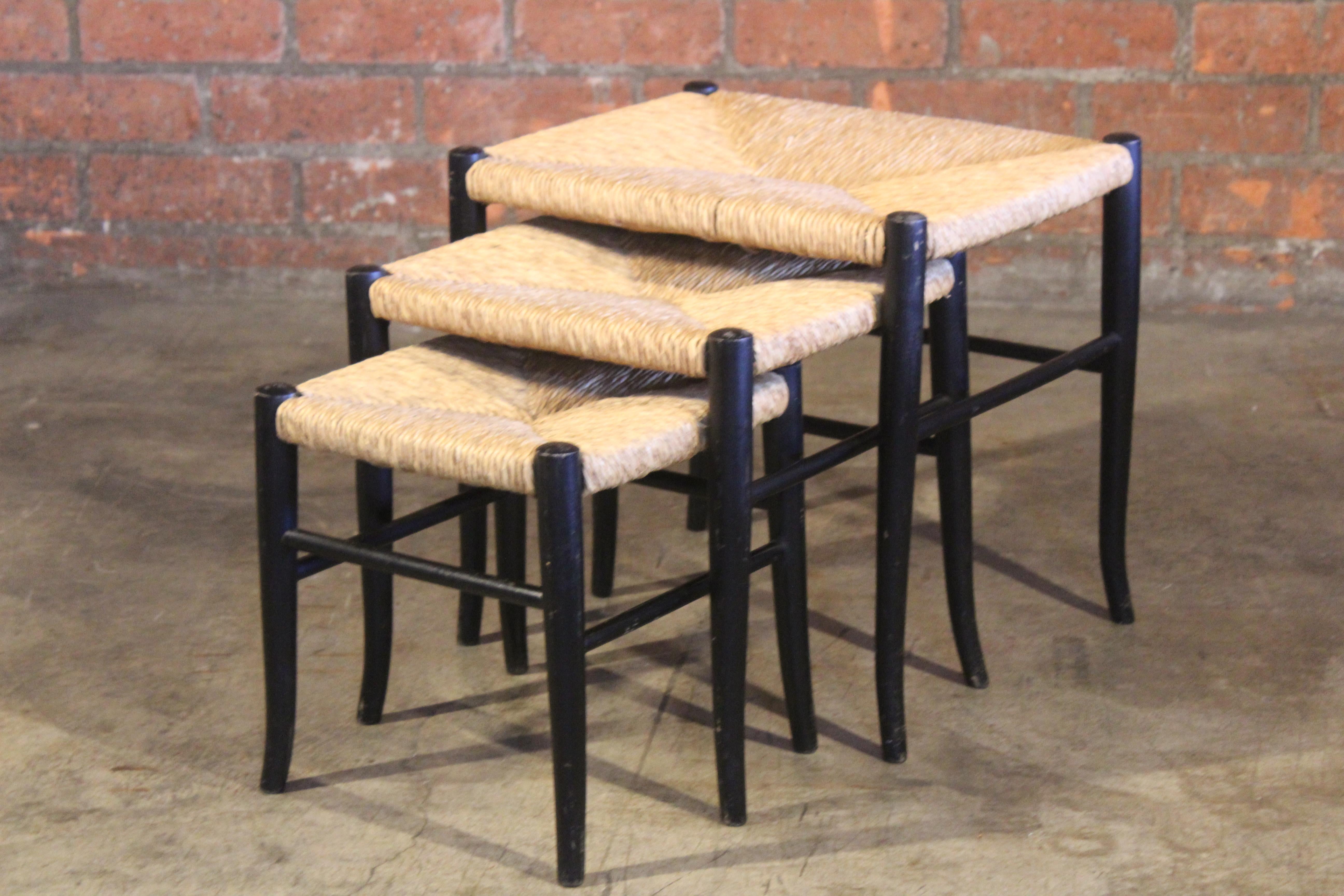 Set of three nesting tables or stools with rush seats. Original black finish. Each stool is in original condition and shows age appropriate wear.