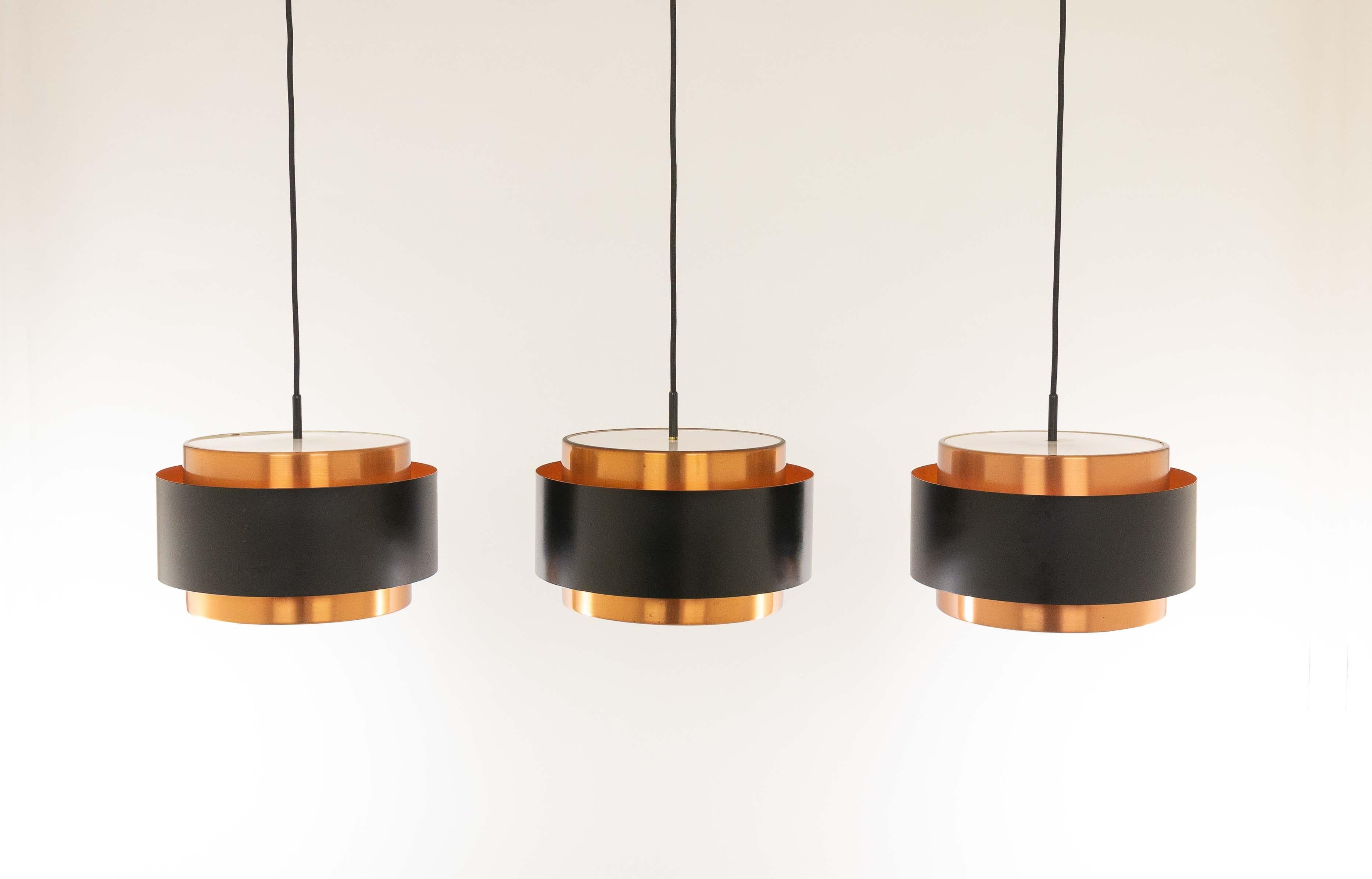 Three Saturn pendants, designed by Danish designer Jo Hammerborg and manufactured by Fog & Mørup.

The model is a structure of two concentric cylindrical copper bands that are held together by a black lacquered band. At the top and the bottom, the