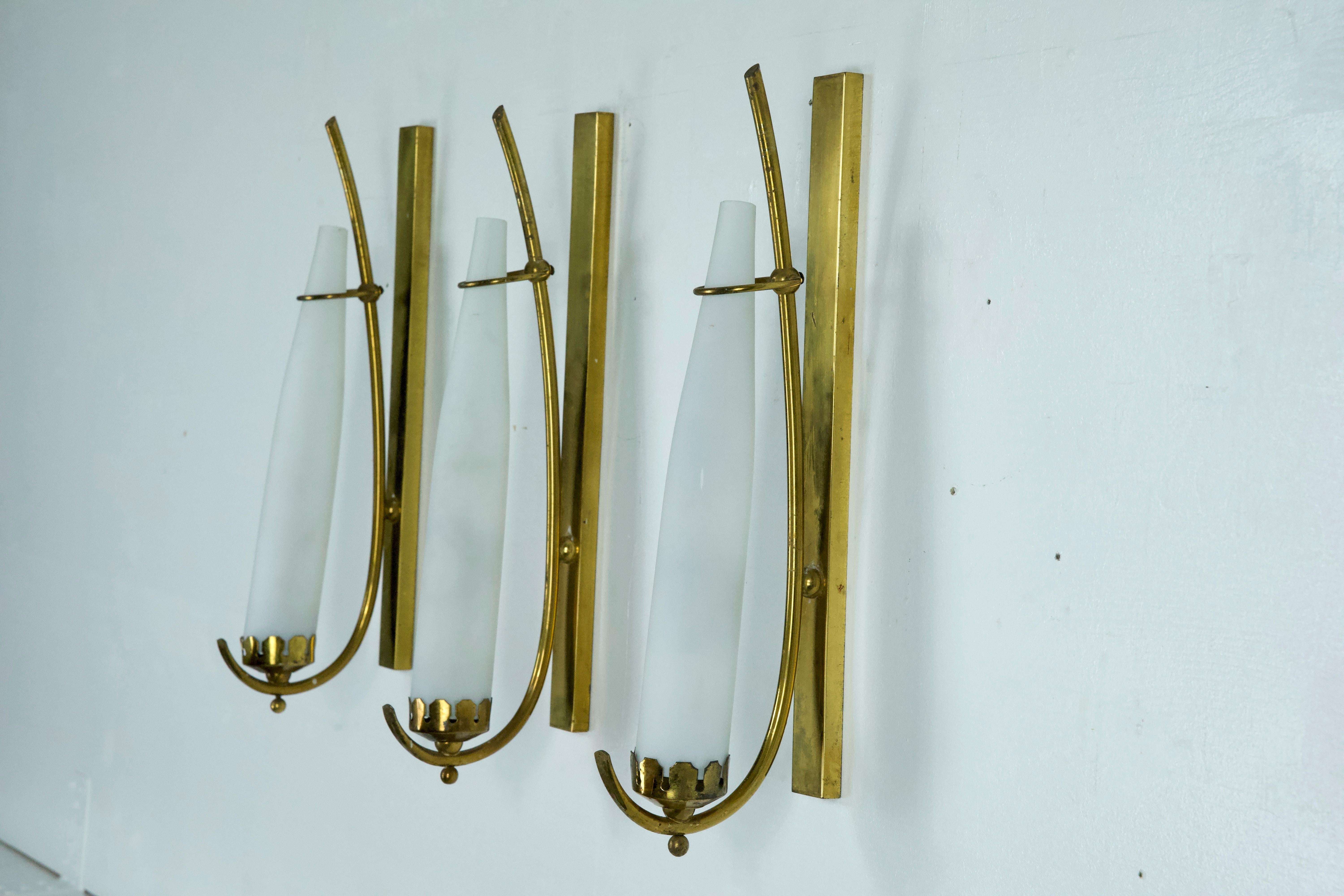 Set of three sconces in brass and triplex opaline glass, manufactured in Italy in the manner of Arredoluce Monza. Original vintage condition with trace of age and use, patina on the brass. No chips or cracks. Full working with EU standard, adaptable