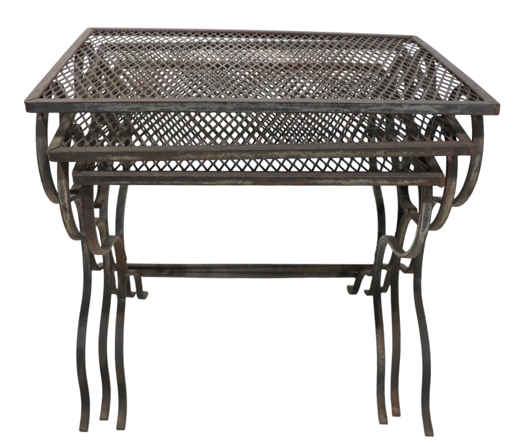 Chic set of three garden, patio, poolside tables attributed to Woodard, or possibly Salterini. The tables are graduated in size, and  feature wrought iron frames with metal mesh tops - all are in good, original vintage condition showing some
