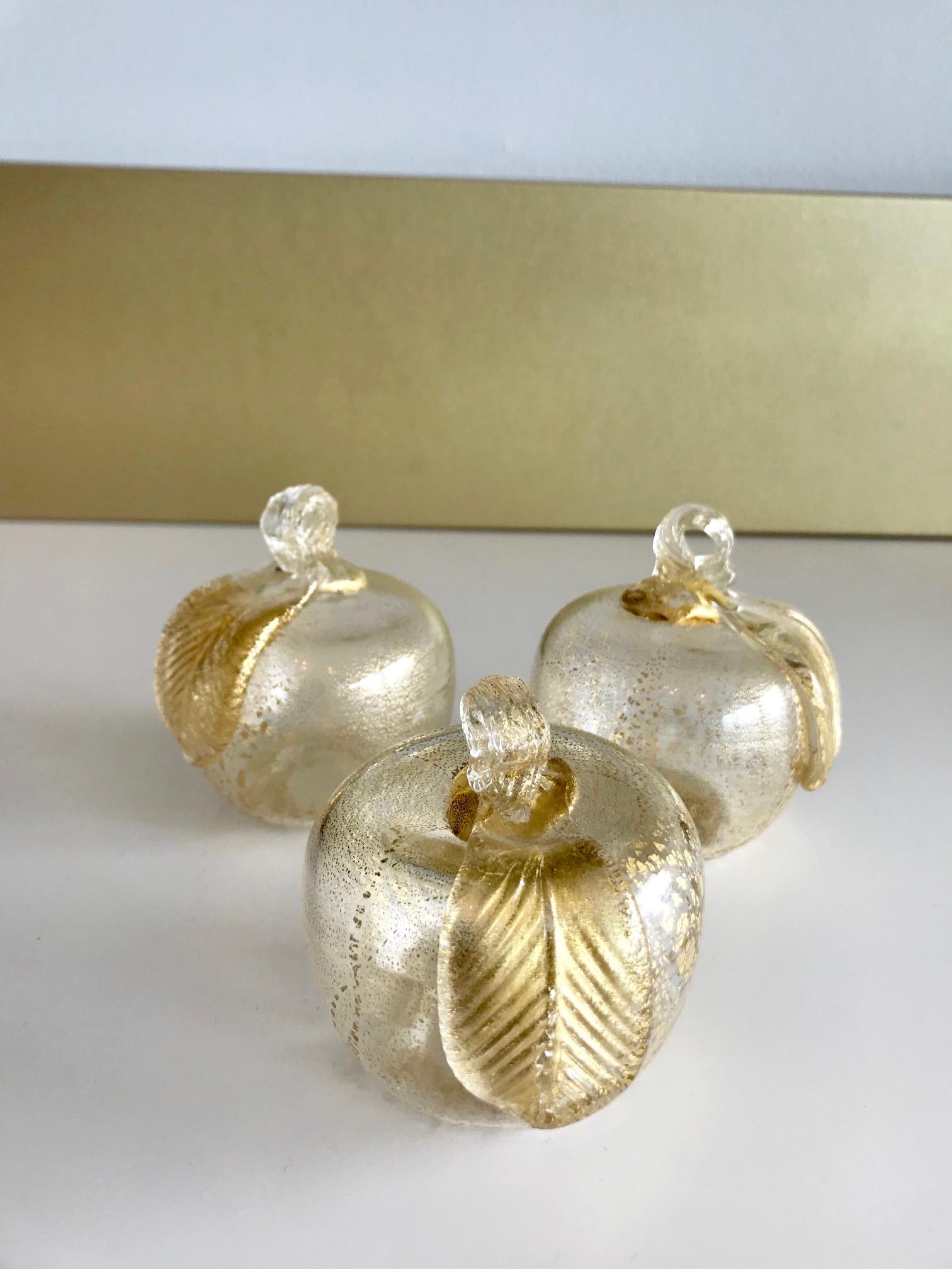 Set of three gorgeous hand blown Murano figurines in the form of apples with 24-karat gold mica flecks. The apples feature gorgeous scrolled stems with stylized fluted leaf detail. Great as table top or desk accessories.