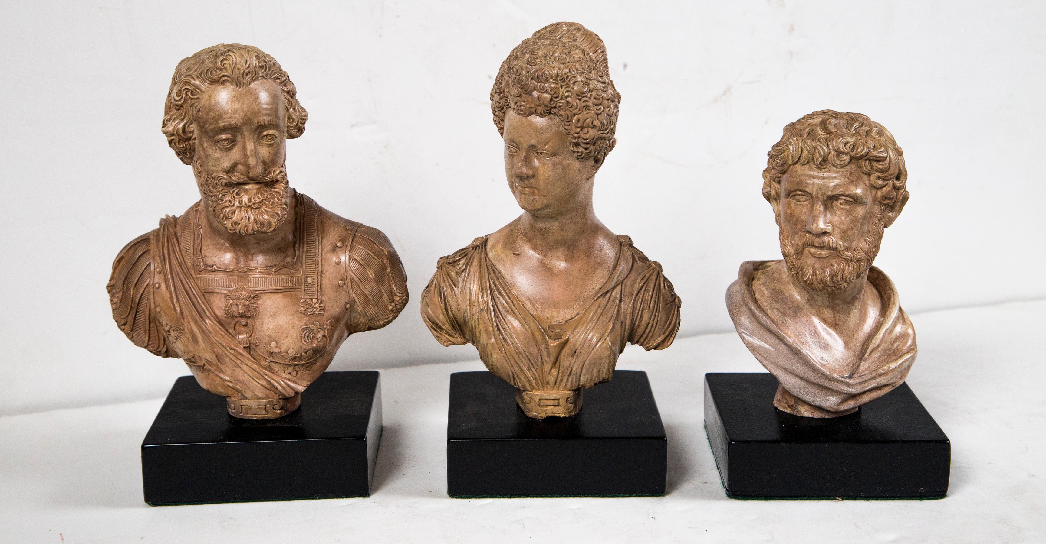 Made of cast or molded plaster with a pale brownish glaze. each set on a black painted wood base measuring 4.75 square and about 1.5 inches in height
.
The tallest of the three, is the female bust,, She is the tallest of the three. With her curls