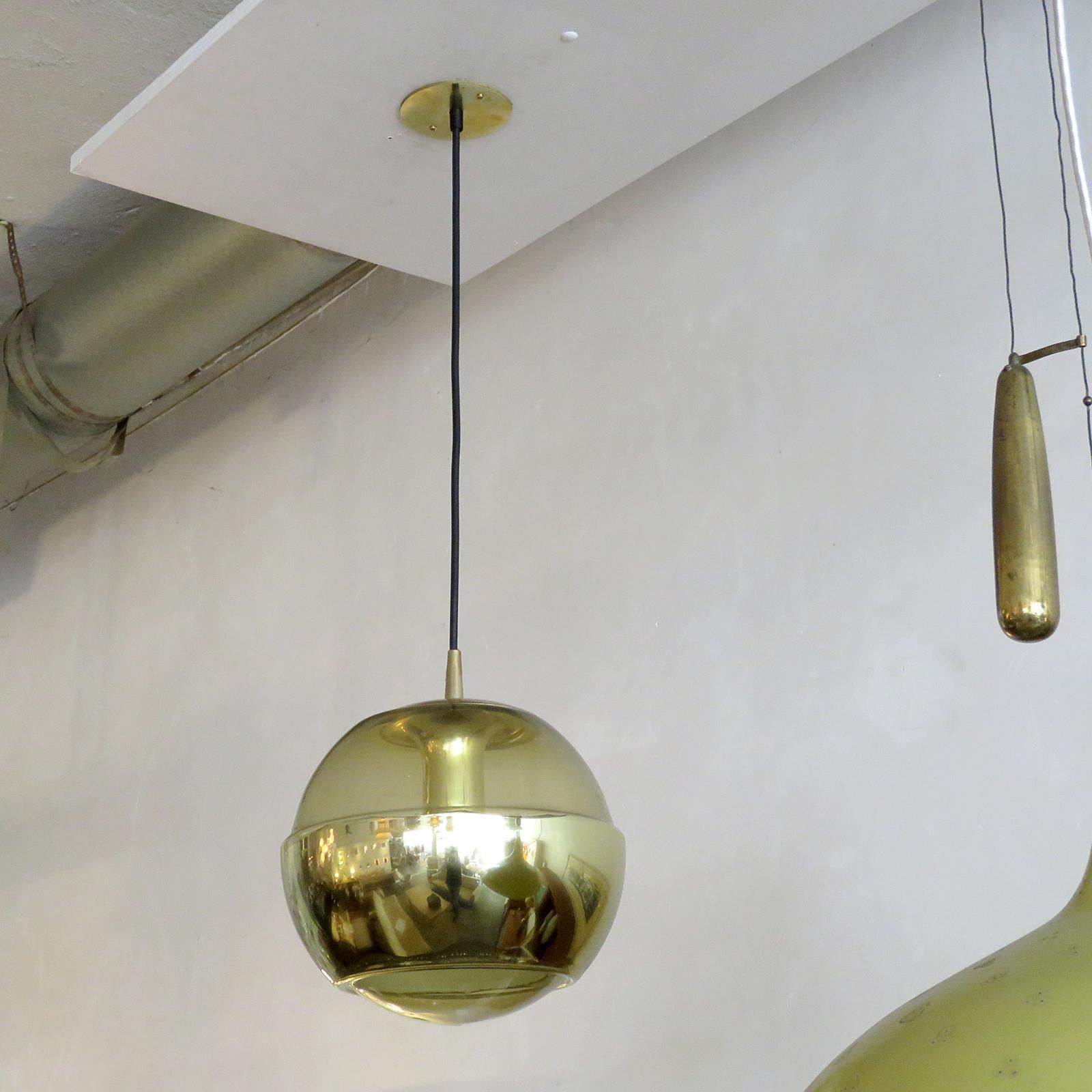 molded, smoked glass hanging fixtures by Peill & Putzler, with an opaque, brass colored layer across the bottom part of the globes, brass colored hardware and custom solid brass canopy, wired for US standards, one E27 socket per fixture, max.