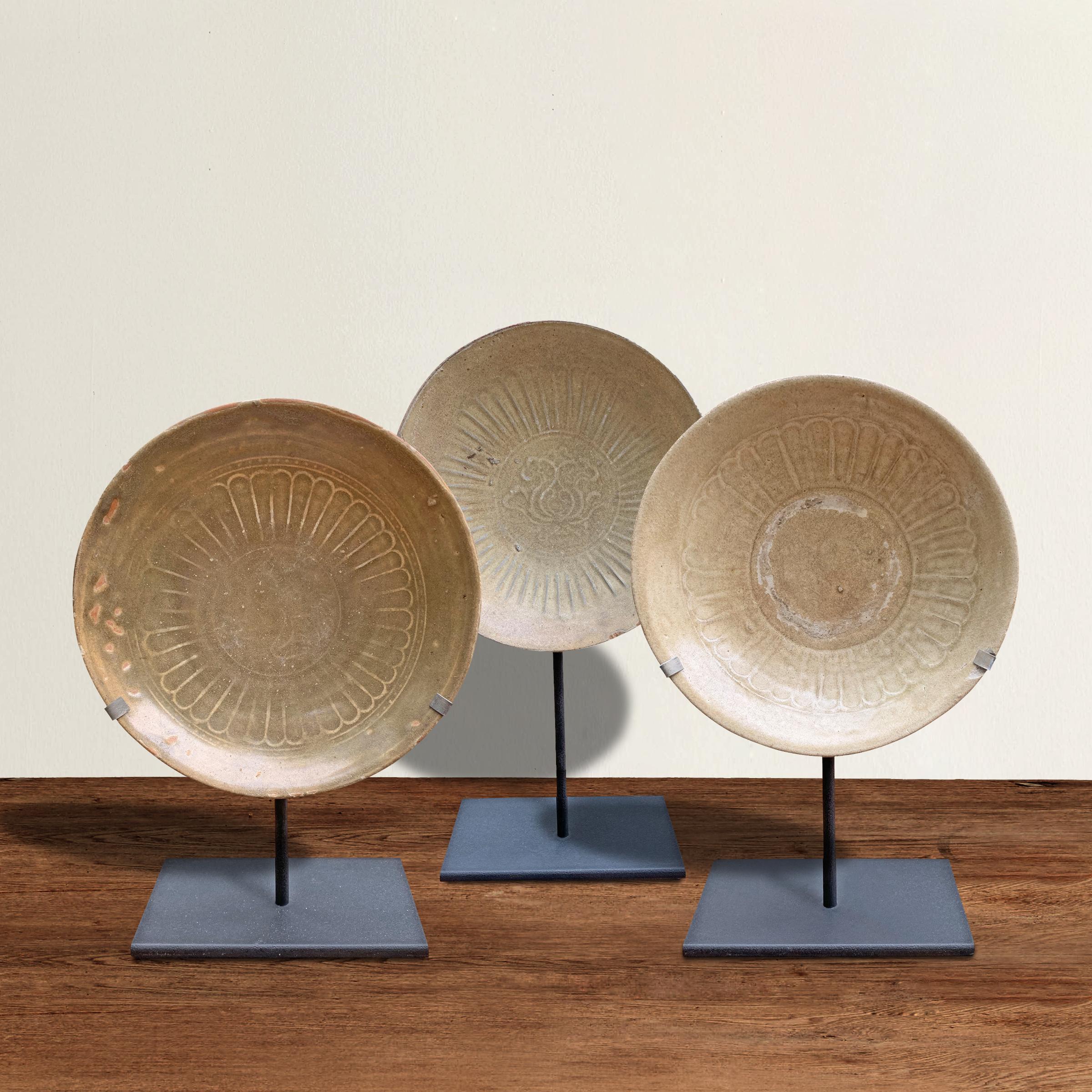 A wonderful set of three Chinese Song Dynasty (960 to 1279 AD) glazed stoneware bowls, each with its own unique lotus flower decoration, and all with beautiful soft beige and green glazes, and mounted on custom steel stands.