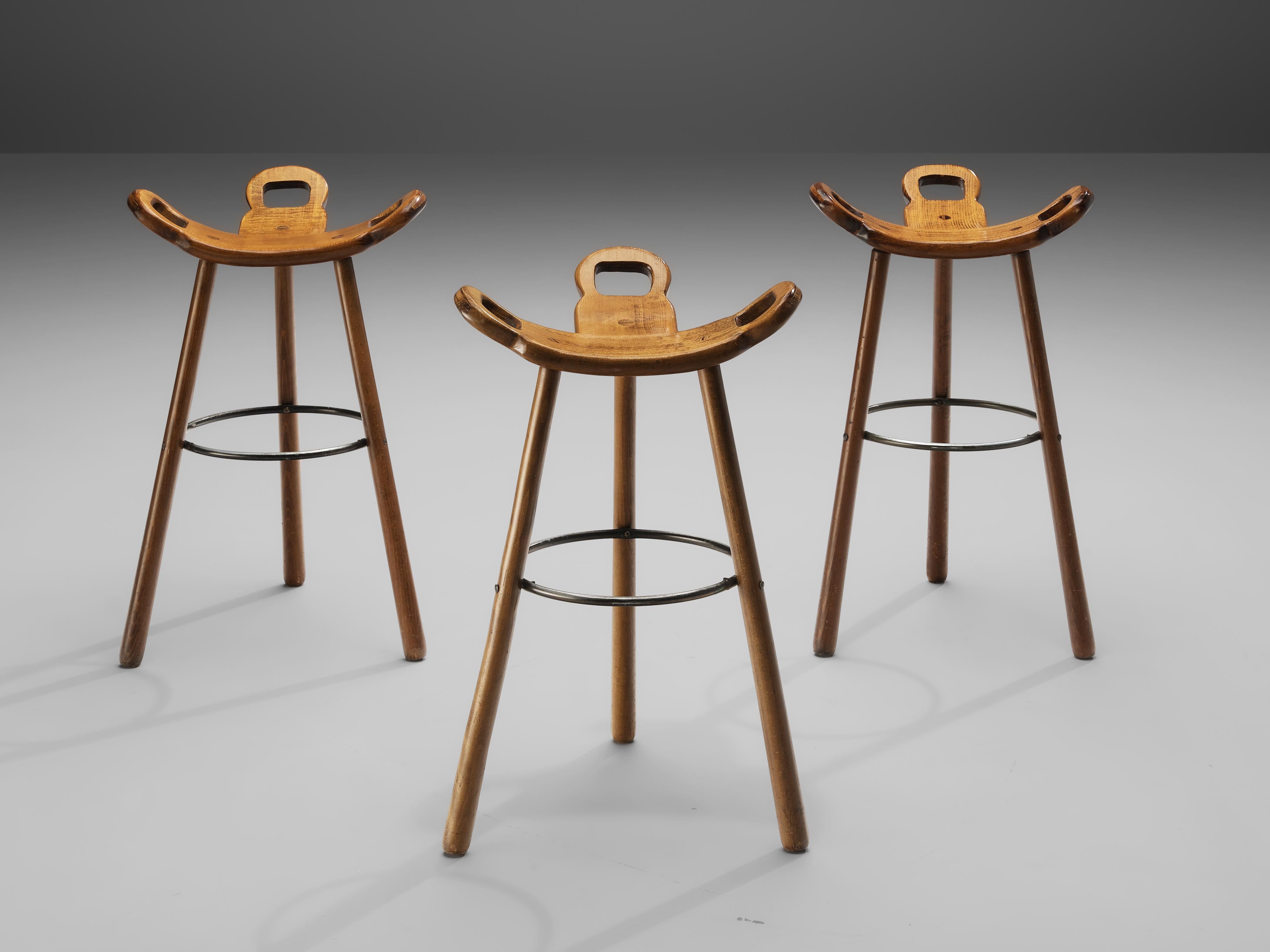 Set of three 'Brutalist' or 'Marbella' bar stools, stained beech, metal, Spain, 1970s

Brutalist bar stools in stained beech. The eye-catching part is the seating which is a curved T-shape with three handles. The handles are not only an interesting