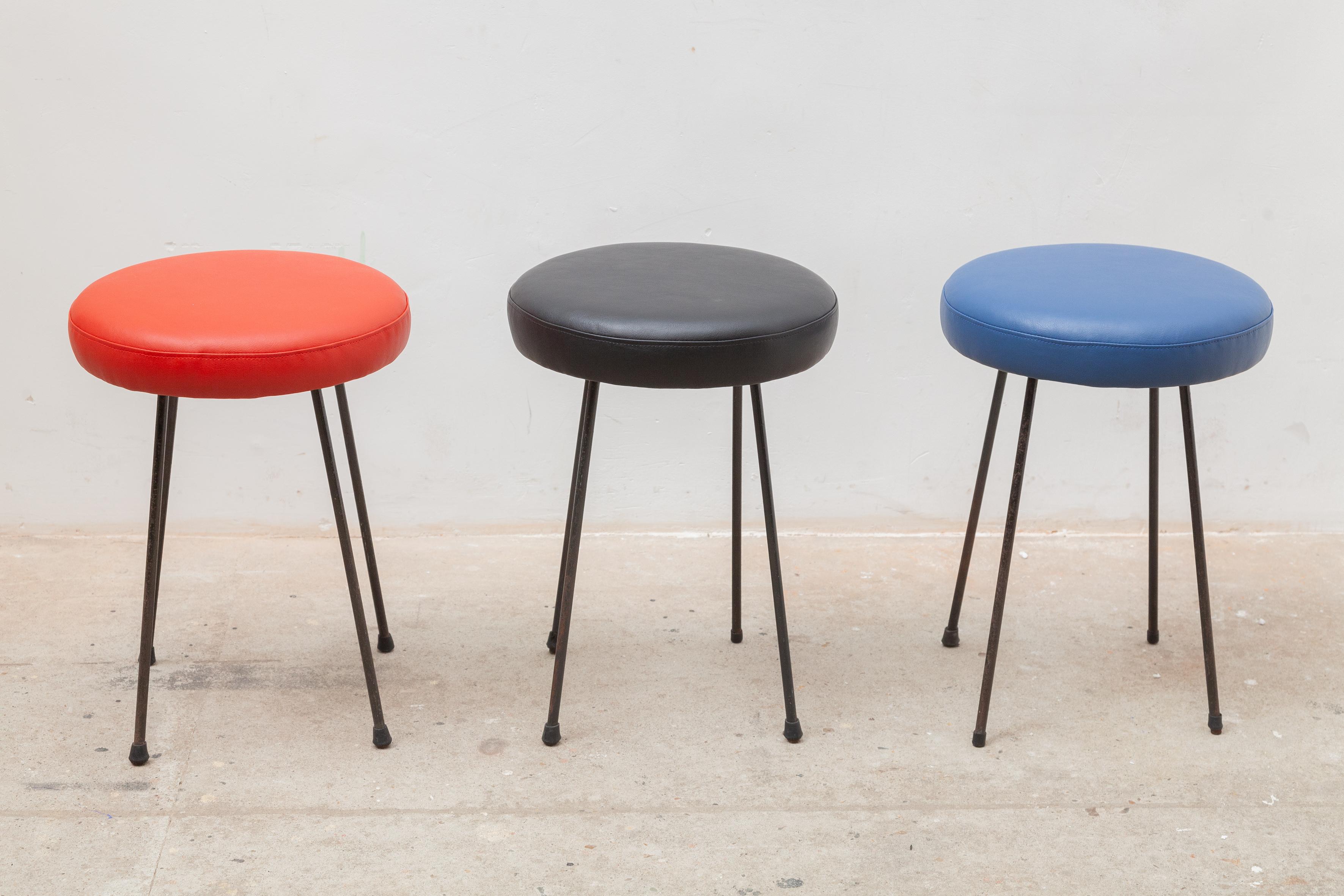 Midcentury Modern fifties set of three stools with new leather upholstery seats in the colors red, blue and black at iron legs. Very stable and a nice accent in your interior.