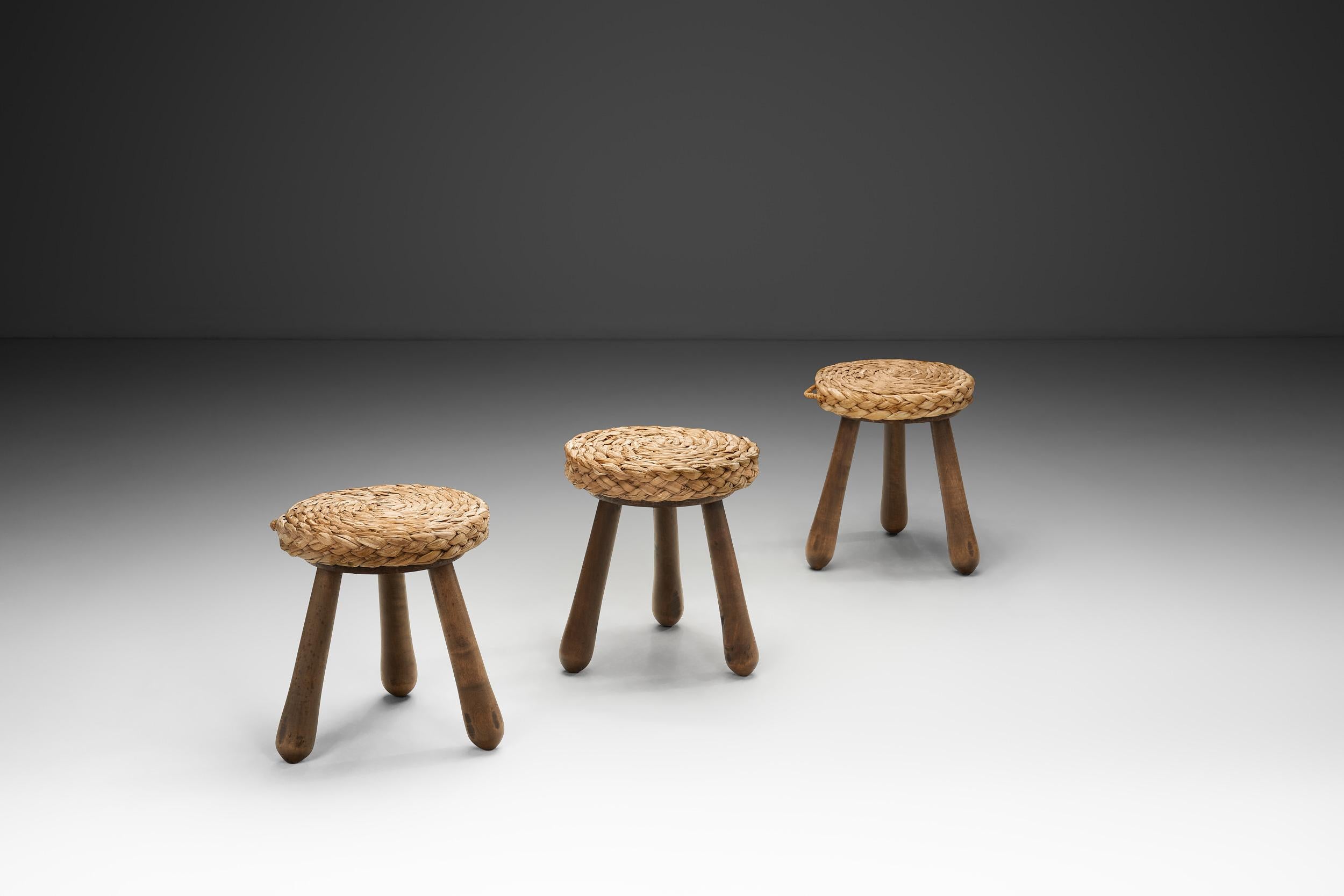 Questo bellissimo set di sgabelli è realizzato alla maniera del duo di designer francesi Audoux-Minet. Adrien Audoux e Frida Minet hanno lavorato insieme a metà del XX secolo. Il duo è noto per l'uso innovativo di materiali naturali e sostenibili,