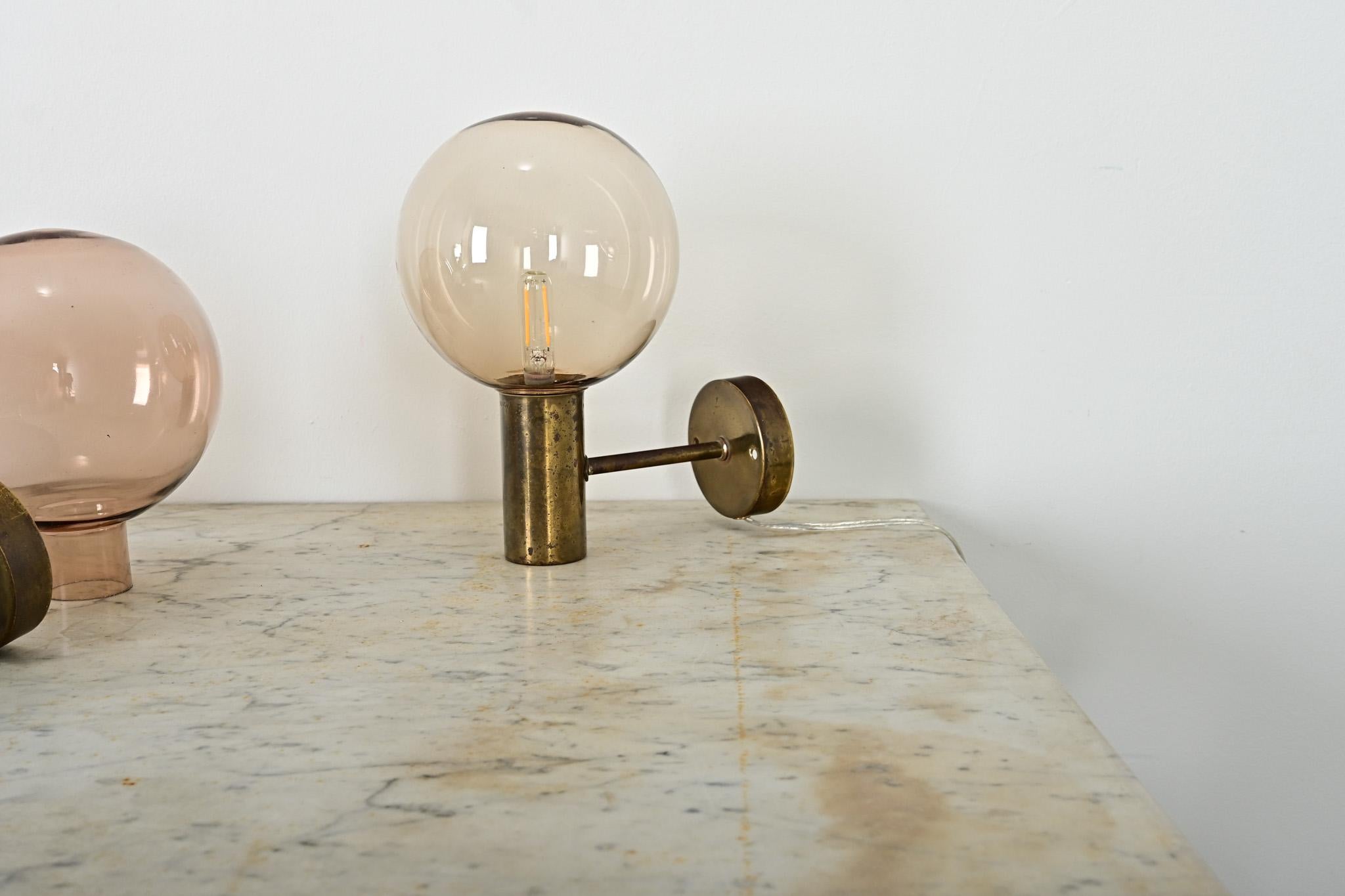 Vintage set of three Swedish brass & smoked glass wall sconces designed by Hans-Agne Jakobsson for AB Markaryd, known as the model V-149, circa 1960. Spherical globe diffusers cast an amber glow through the smoky glass, ideally with small