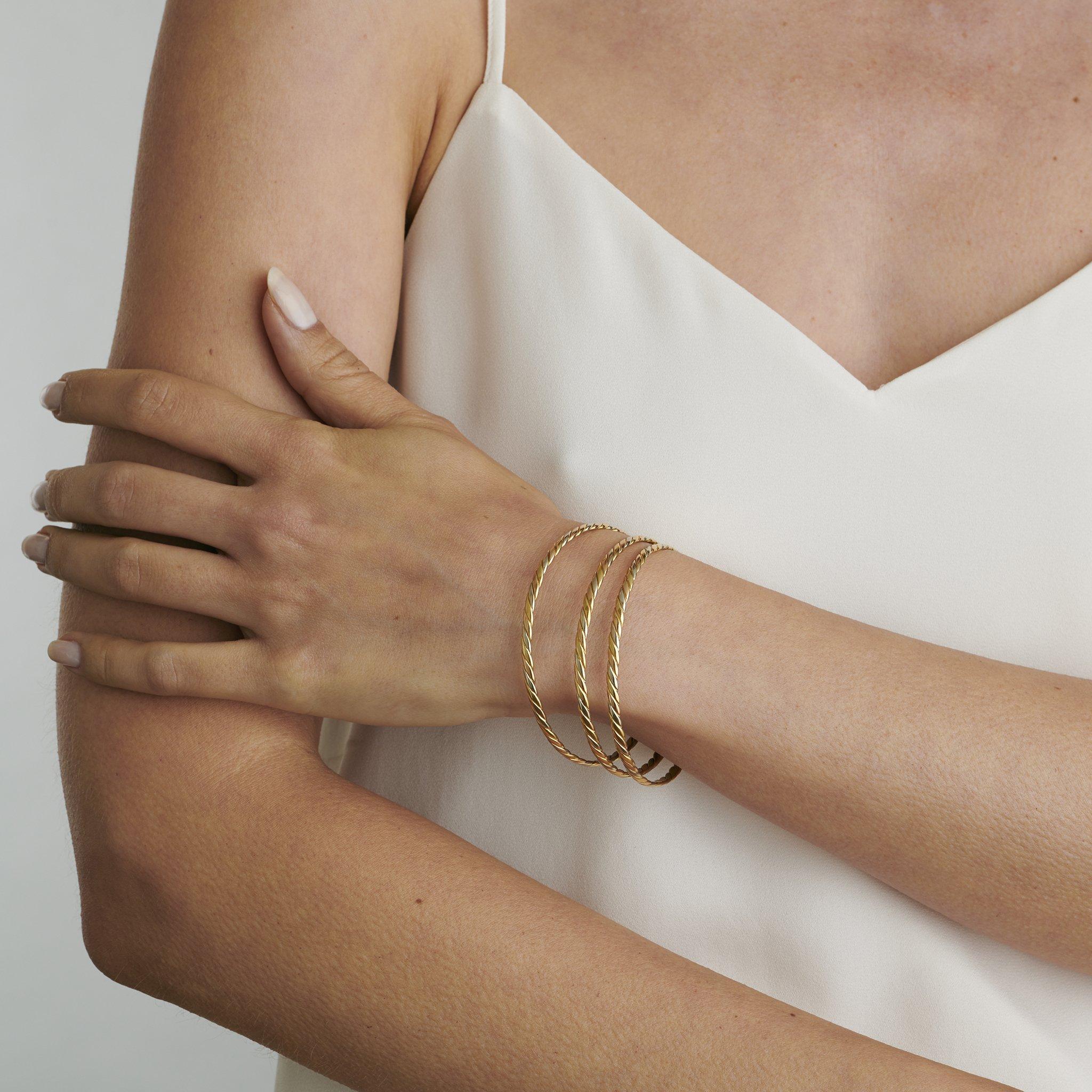Dating from the 1970s, this trio of bracelets is composed of tri-color gold. The set of three identical narrow bangles follows a repeating yellow, white, and rose-gold ropetwist design. With their refined French workmanship, these fun 1970s