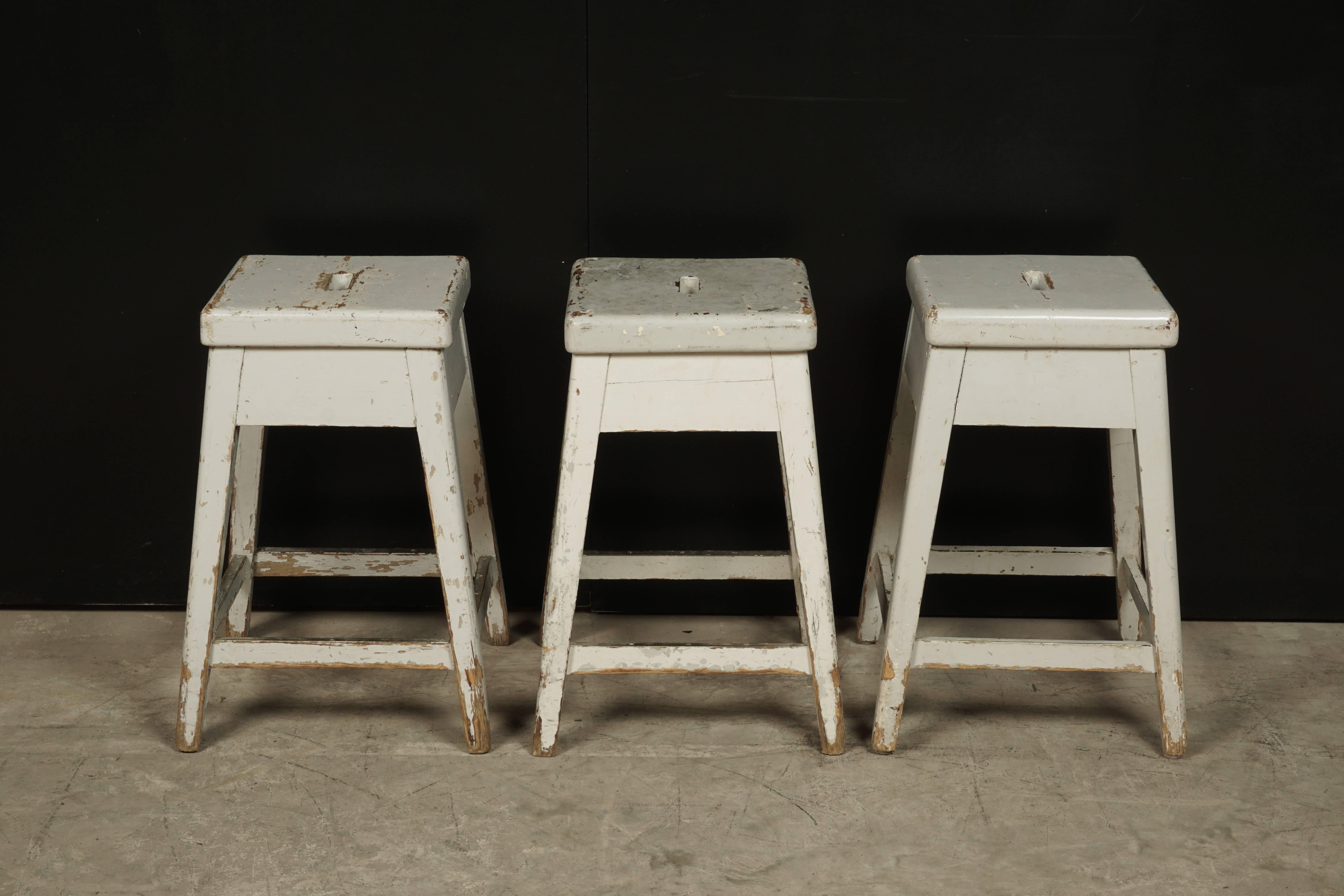 Set of three University stools from Sweden, circa 1920. Original Grey paint with brass supports on foot rests.