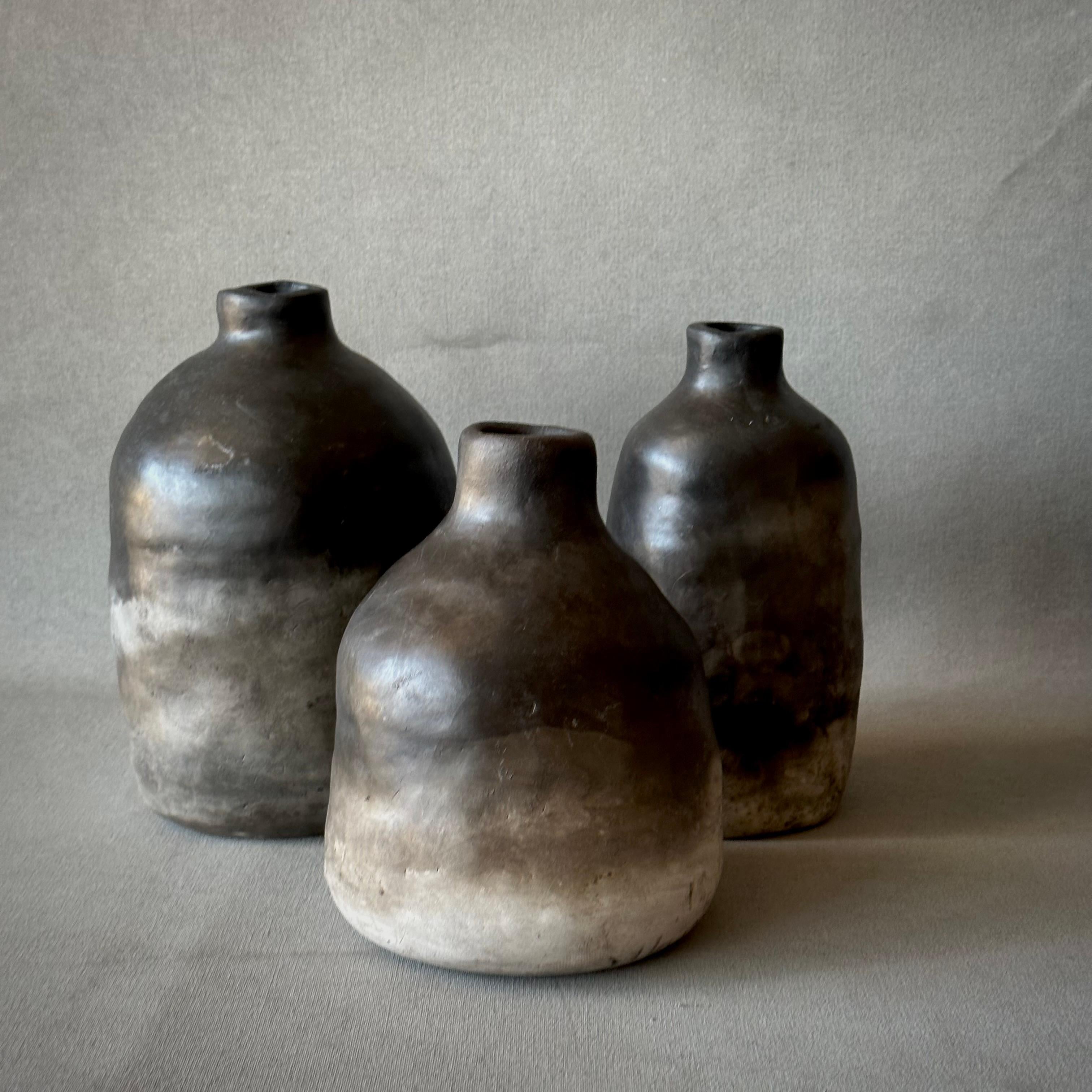 Set of three ceramic pottery vessels by contemporary Dutch artist Carine Despriet. Earthy and organic, with softly rounded bases and small tapered lips. This collection would work especially well as a set of bud vases. Their rich espresso toned