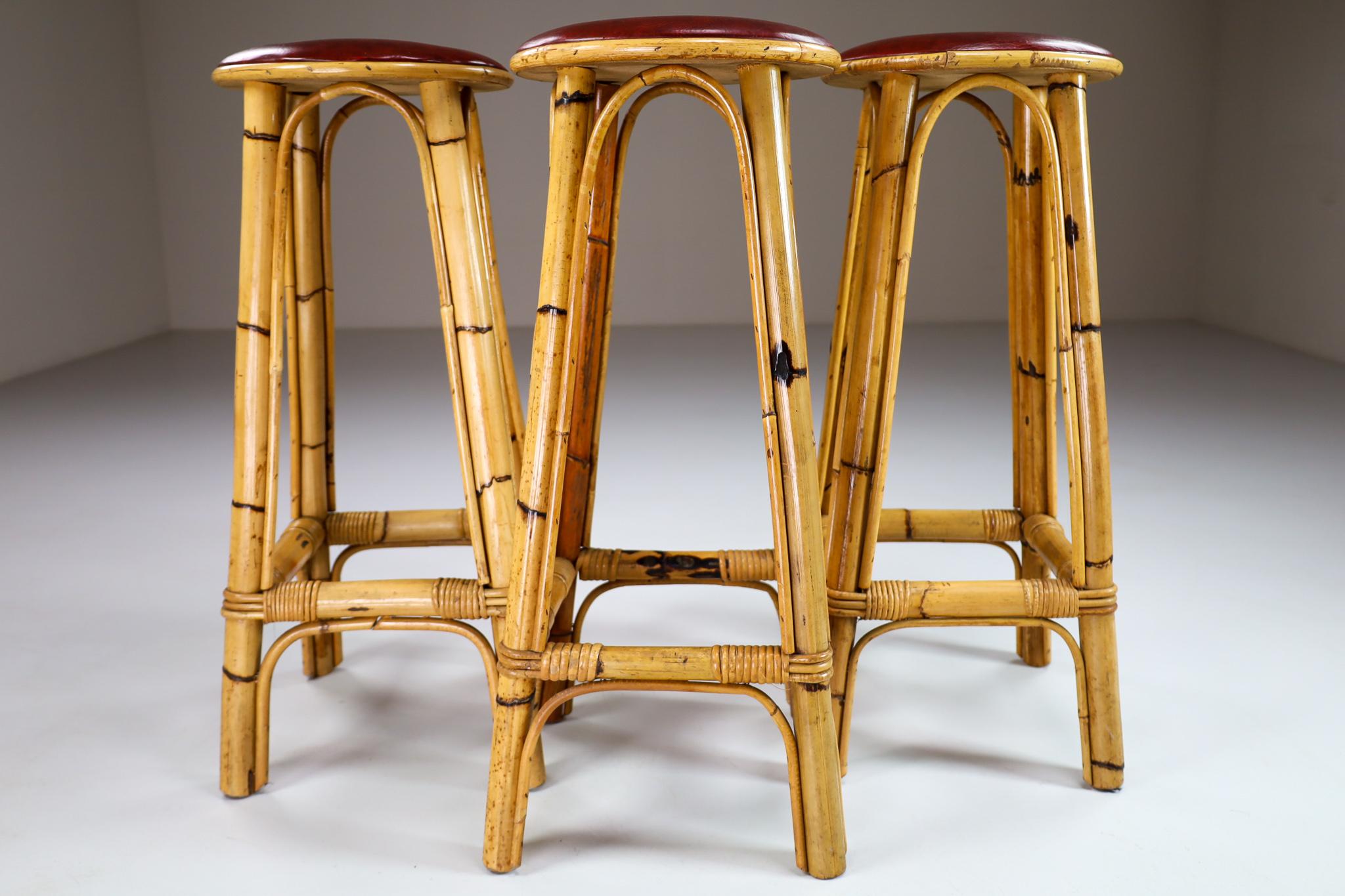 Set of three vintage bamboo barstools with red leather seats. Made in France in 1950s. With minor signs of wear, a very good condition. Hard-wearing and built for commercial duty, these in-demand stools would be equally at home in a cafe bar,