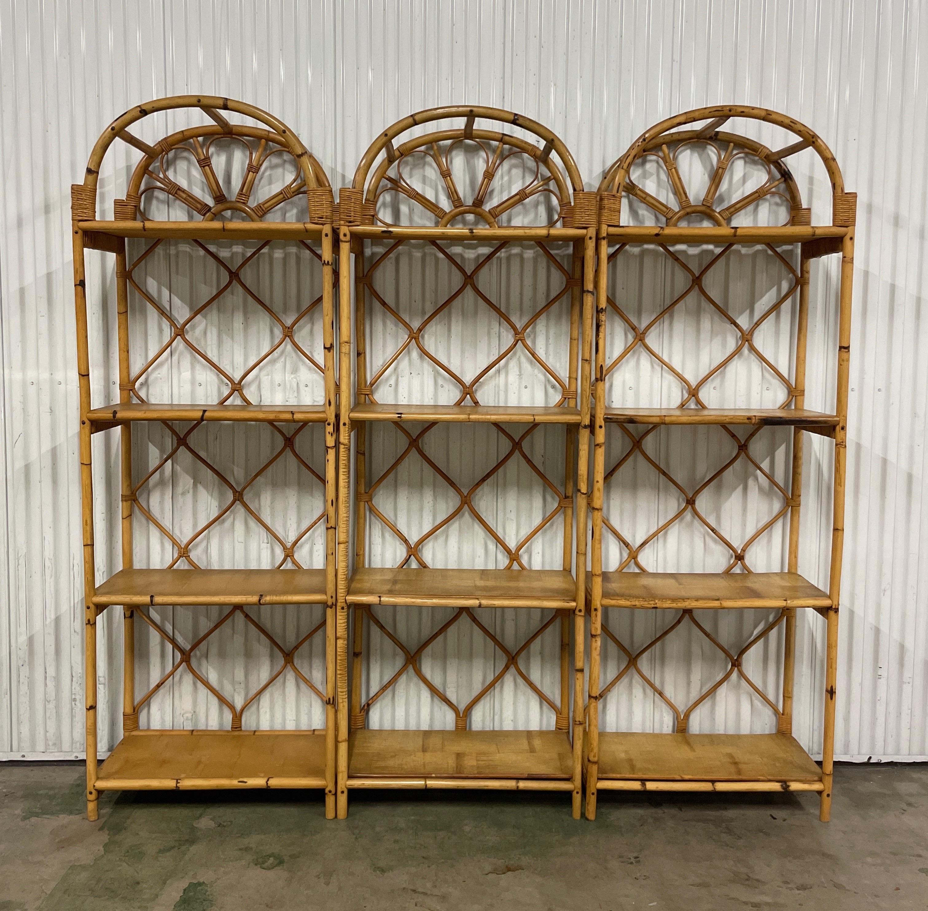 Vintage set of three Sunburst Rattan & bamboo etageres. Each etagere has four wood shelves. They can be used together as one large wall unit or can be used separately.