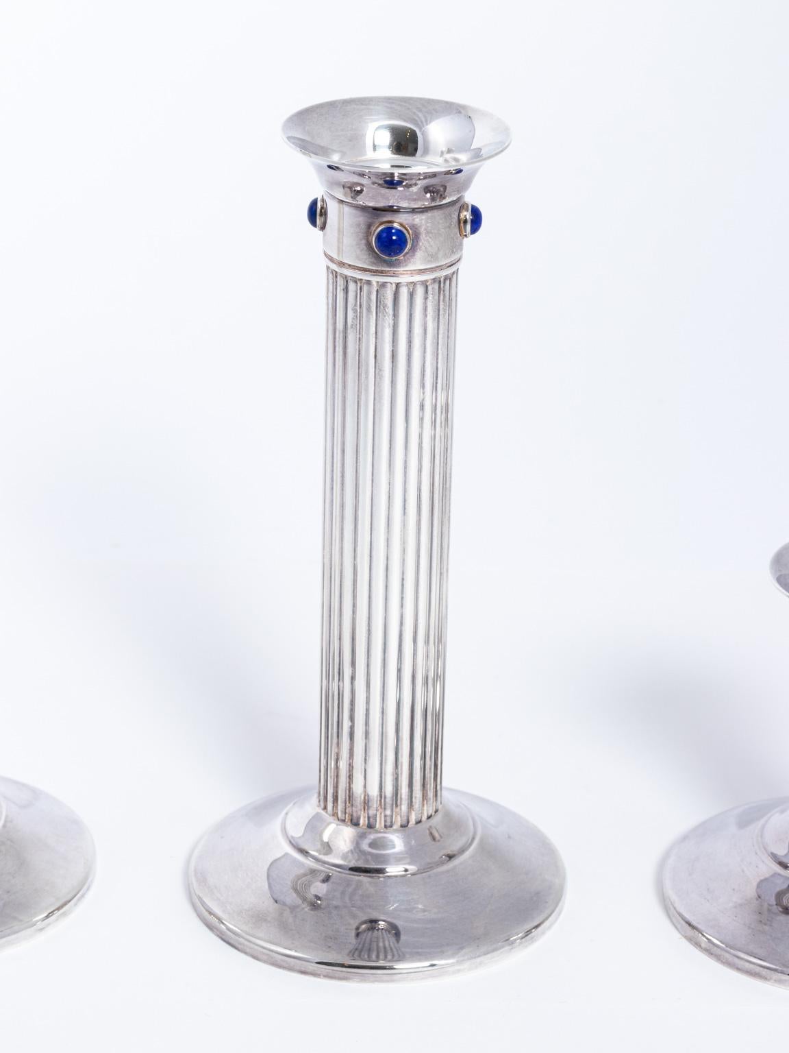 Vintage Cartier fluted silver plate candlesticks embellished with blue lapis stone on the capitals. Includes one tall, one medium, and one small candlestick. Brand stamp is also featured on the underside. Please note of wear consistent with age. The