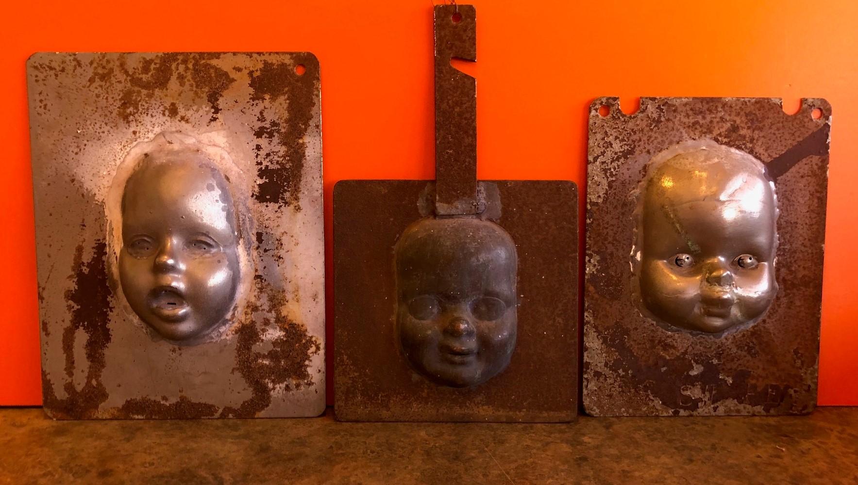 Rare ensemble de trois moules métalliques vintage pour têtes et visages de poupées, vers les années 1930. Les pièces d'aspect industriel sont tout à fait uniques et constituent un excellent article de décoration 
