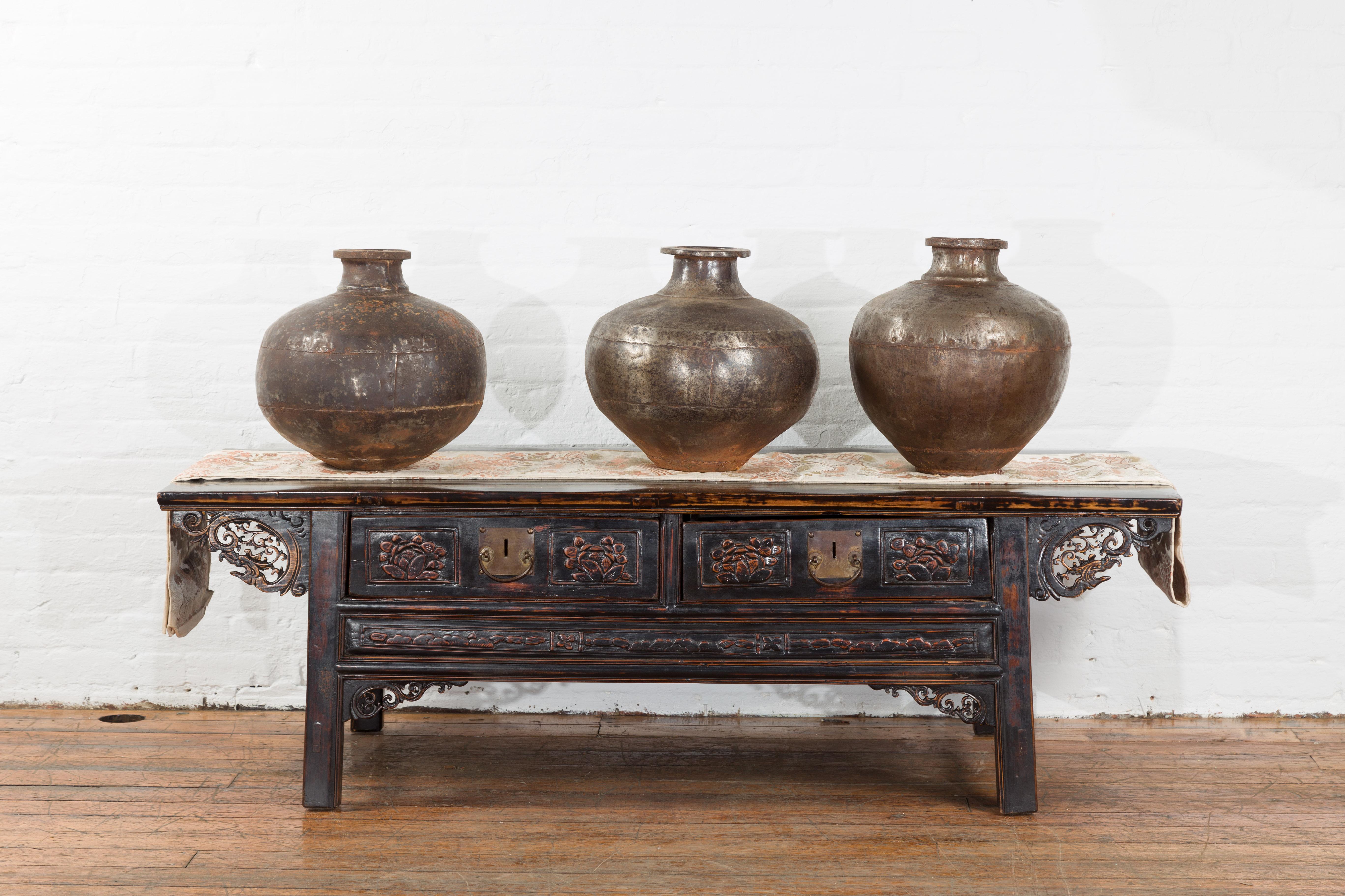 A set of three vintage Indian metal vessels from 20th century, with weathered patina. We have more sets available. Created in India during the 20th century, each of this set of three metal pots features a narrow neck topped with a large lip (with an