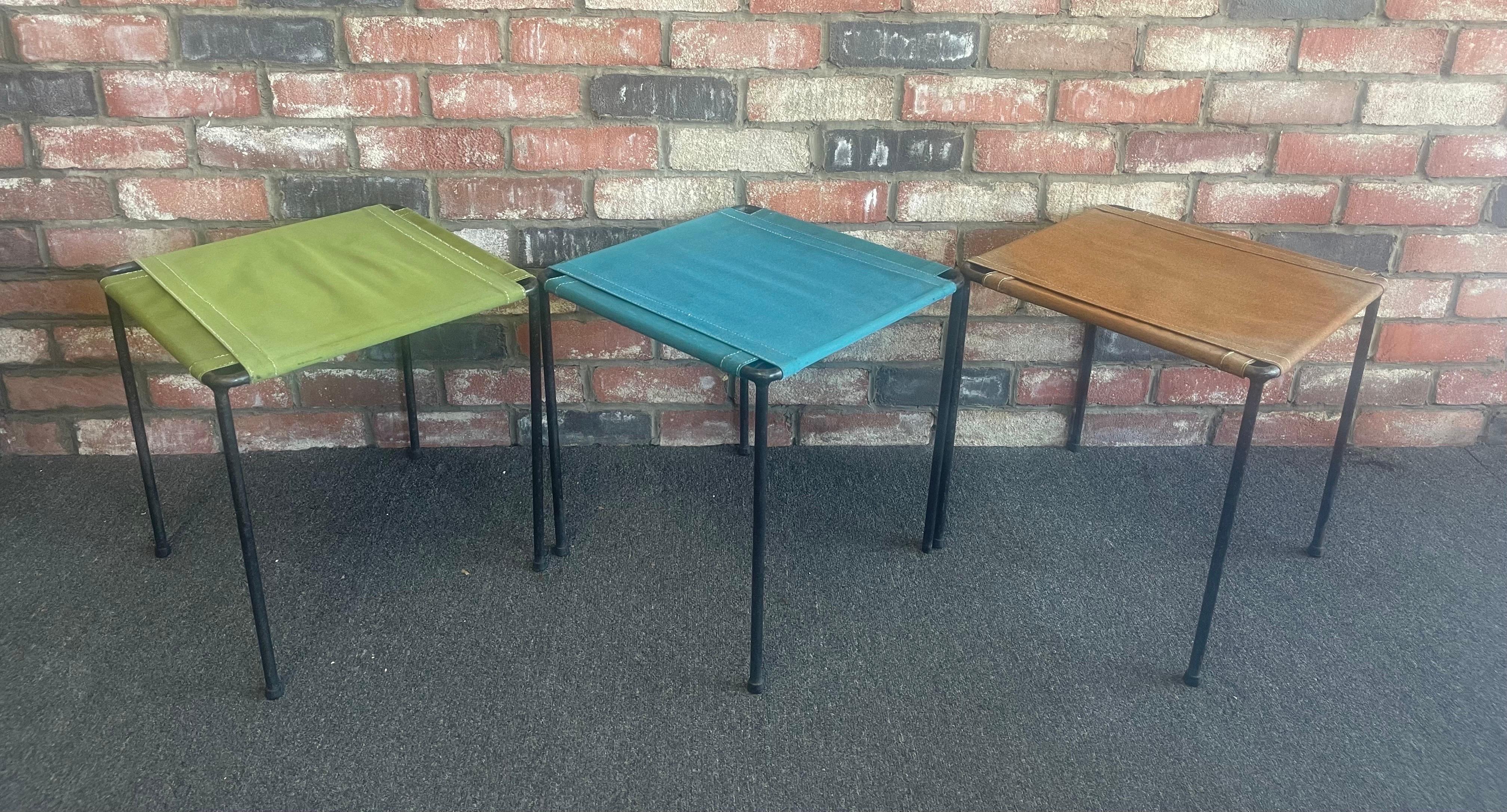 Set of three vintage iron and canvas side tables / stools, circa 1970s. The table bases are forged iron and the tops are marine grade canvas that is tightly wrapped and then tied on top. Very cool and functional pieces that can easily stack for