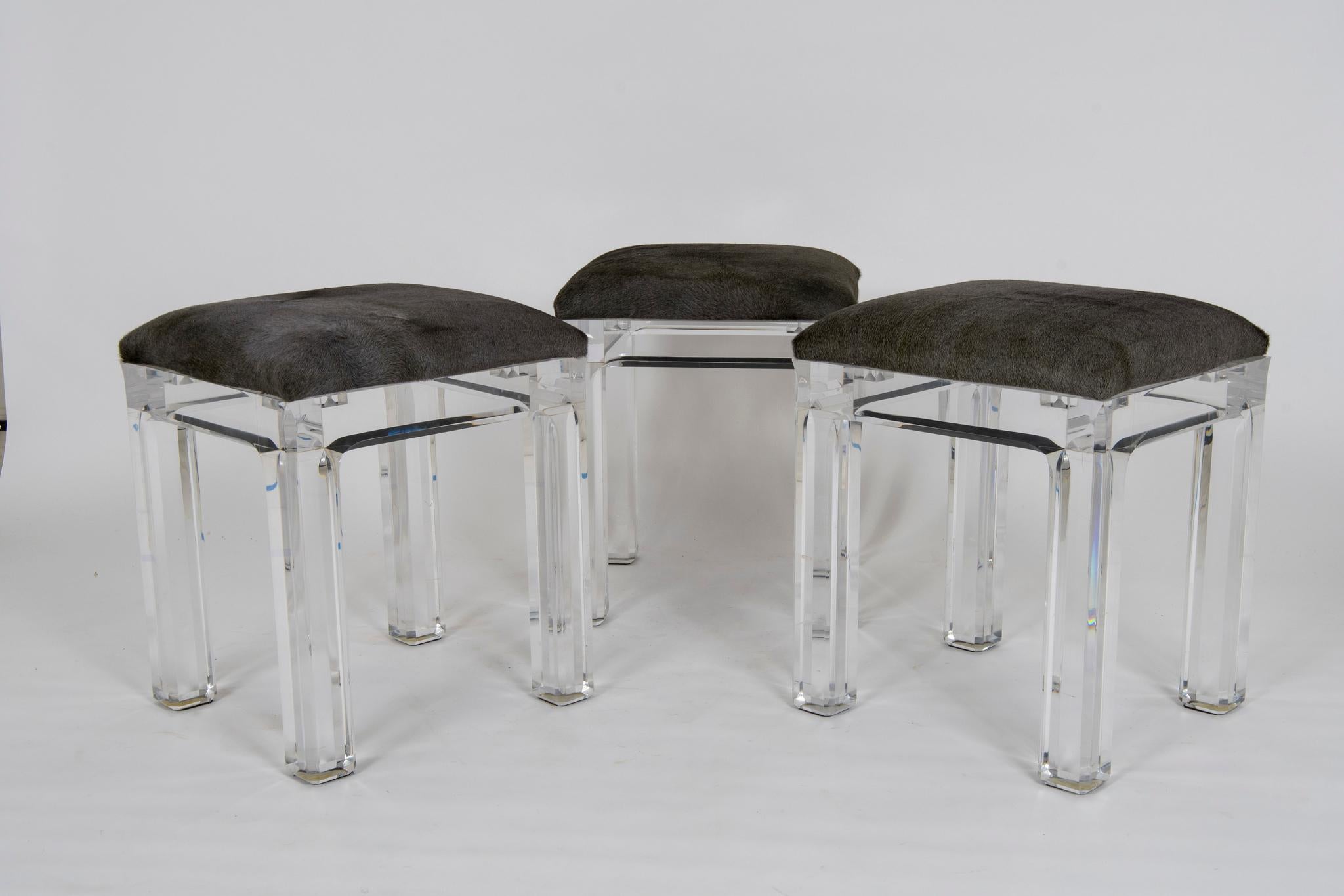 A set of six vintage Lucite counter stools with sturdy block beveled legs and newly upholstered in an acid dyed Italian hair hide. These hides read a silver charcoal gray with slight green blue undertones.