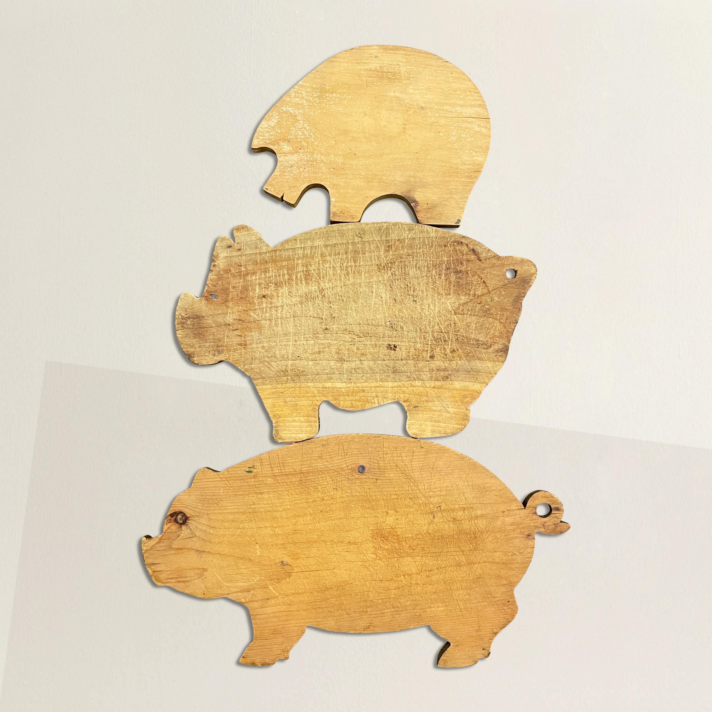 A charming set of three vintage American bucolic pine and maple pig cutting boards, each with their own personality, and including custom wall mounts so you can hang them in your kitchen, pantry, or anywhere else you desire. 

Measures: Small: