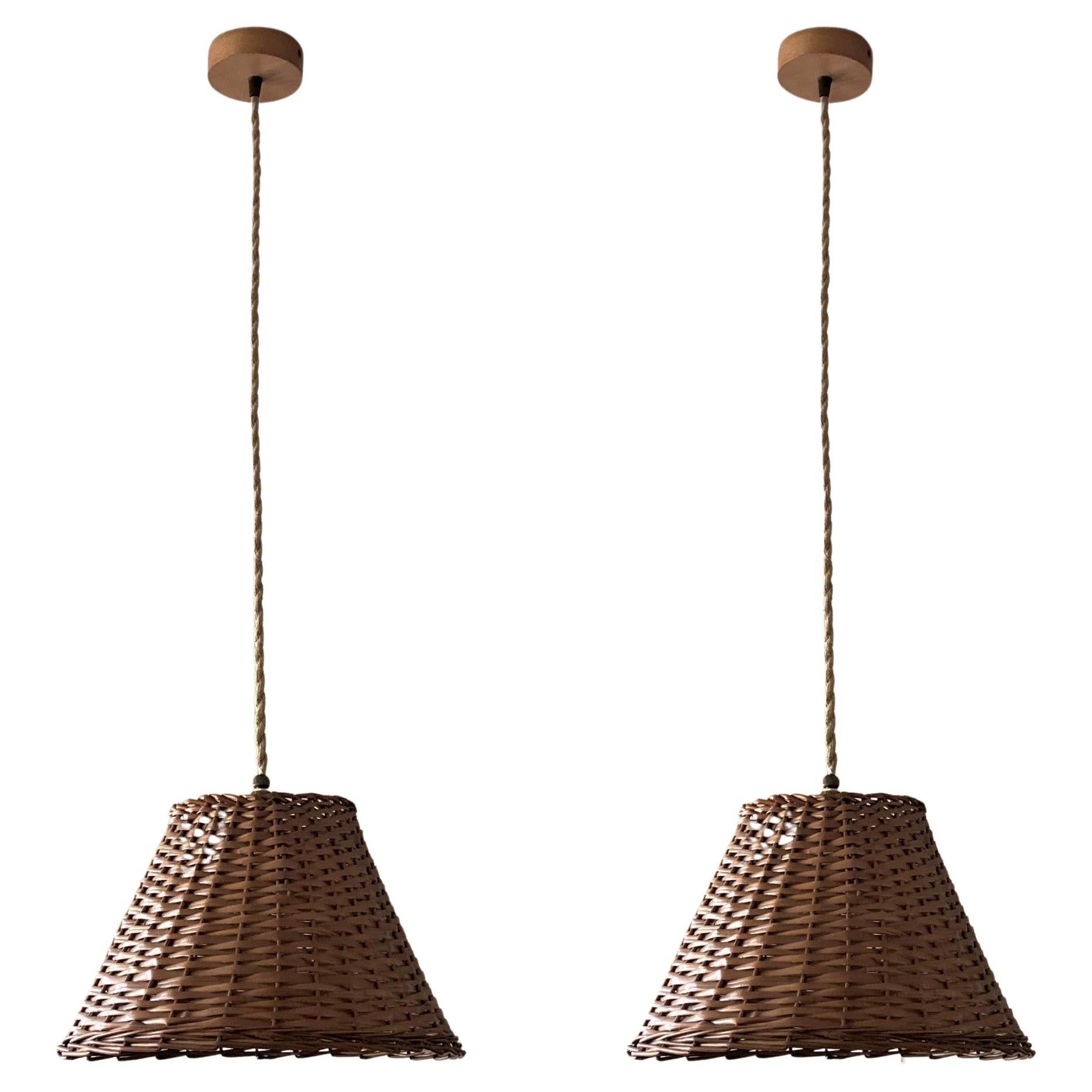 Set of three midcentury rattan pendants, Denmark, 1960s. These beautiful suspension lamps are handcrafted in rattan, lamp shade design with wood canopy. Each pendant with single brass bulb holder for a large sized E27 crew bulb, provinding a warm