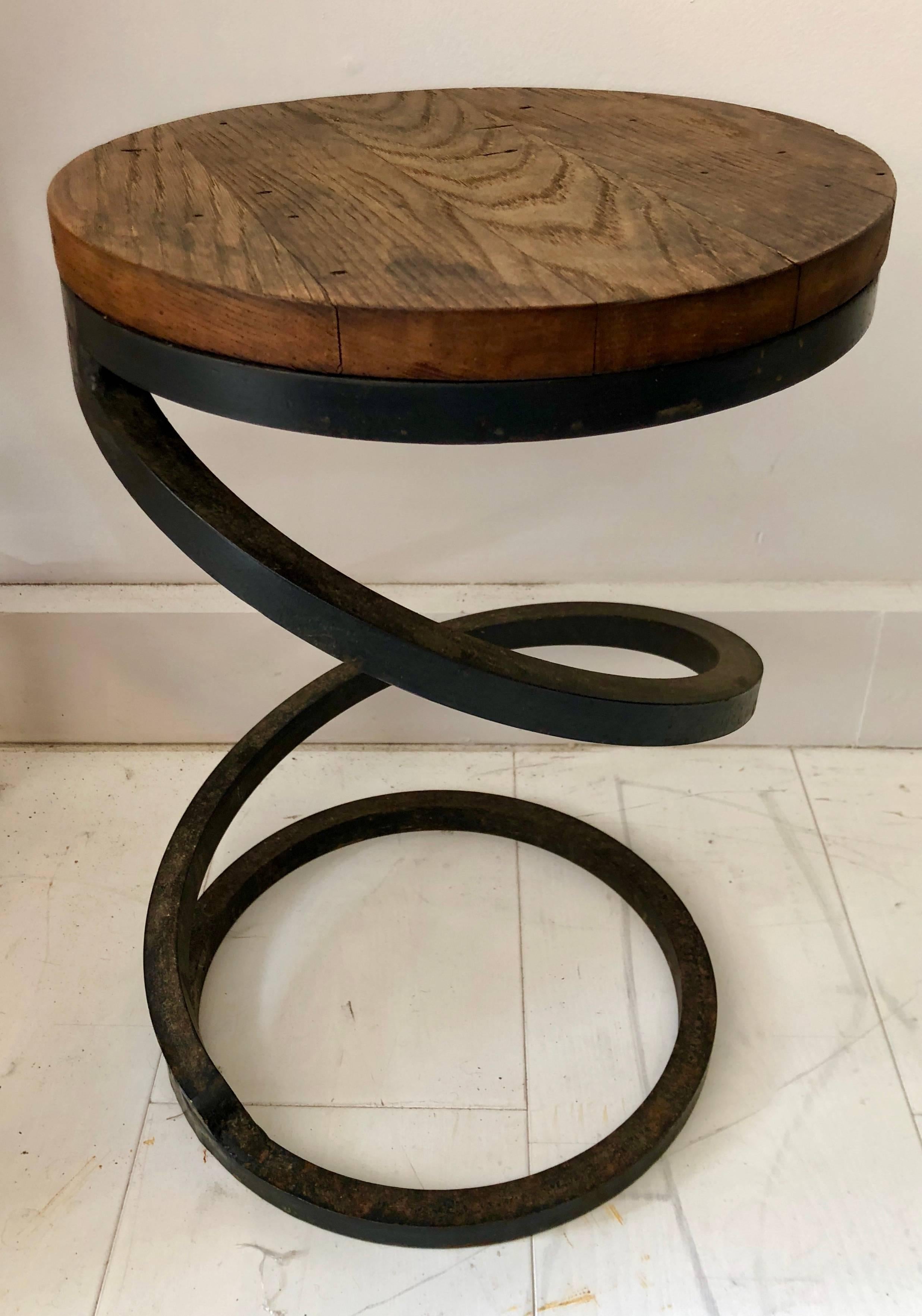 Possibly custom-made, these rustic modern corkscrew-form tables are constructed from heavy solid wrought iron and old repurposed wood tops. All three tables are 12” diameter; heights are 18.75”, 17.5”, and 16.75”. Sold individually.