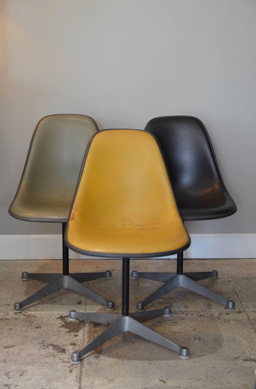 Ensemble de 3 chaises pivotantes Vintage par Eames pour Herman Miller. Un noir, un gris et un jaune foncé.