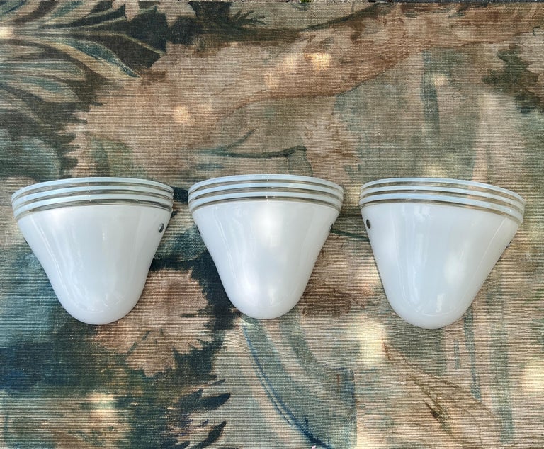 Set of three Mid-Century Modern sconces in white Murano glass designed by Roberto Pamio and Renato Toso for Leucos. The handblown sconces have diffuser shades in white glass and feature clear glass stripes along the top. Each sconce has two metal