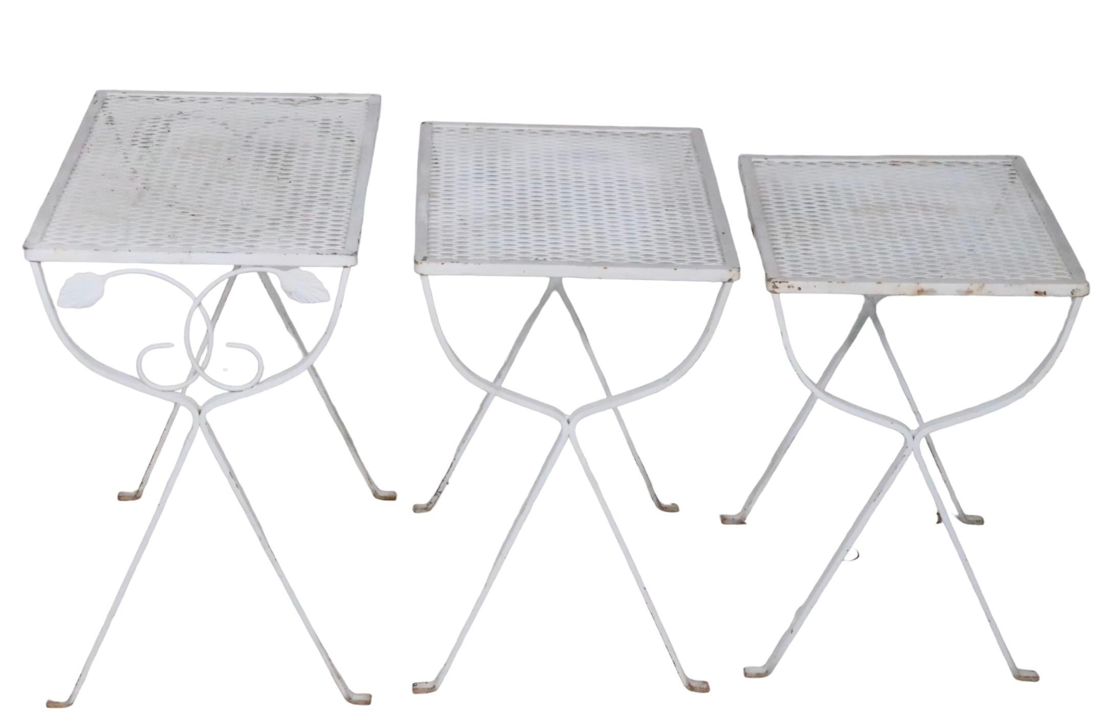 Set of three nesting tables, suitable for indoor outdoor, patio, garden, poolside tables, attributed to Woodard, circa 1950/1970's. The tables have wrought iron bases, with metal mesh tops, all are structurally sound and sturdy, all show some