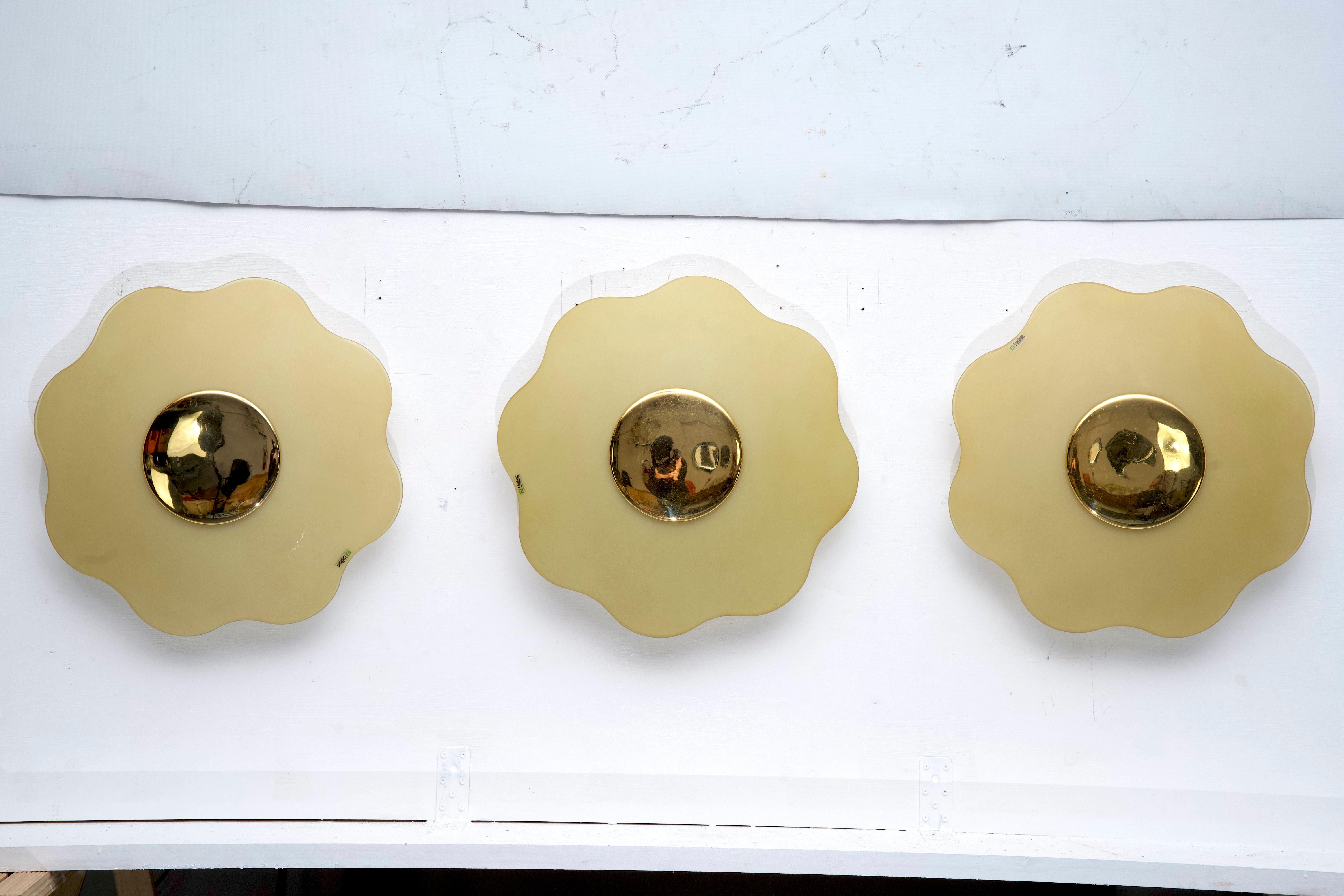 Set of three large wall lamps in murano glass and brass designed by Fabbian and produced in Italy during the late 70s. Great vintage condition with normal trace of age and use. Glasses with no cracks or chips Each sconce mounts six sockets for E14