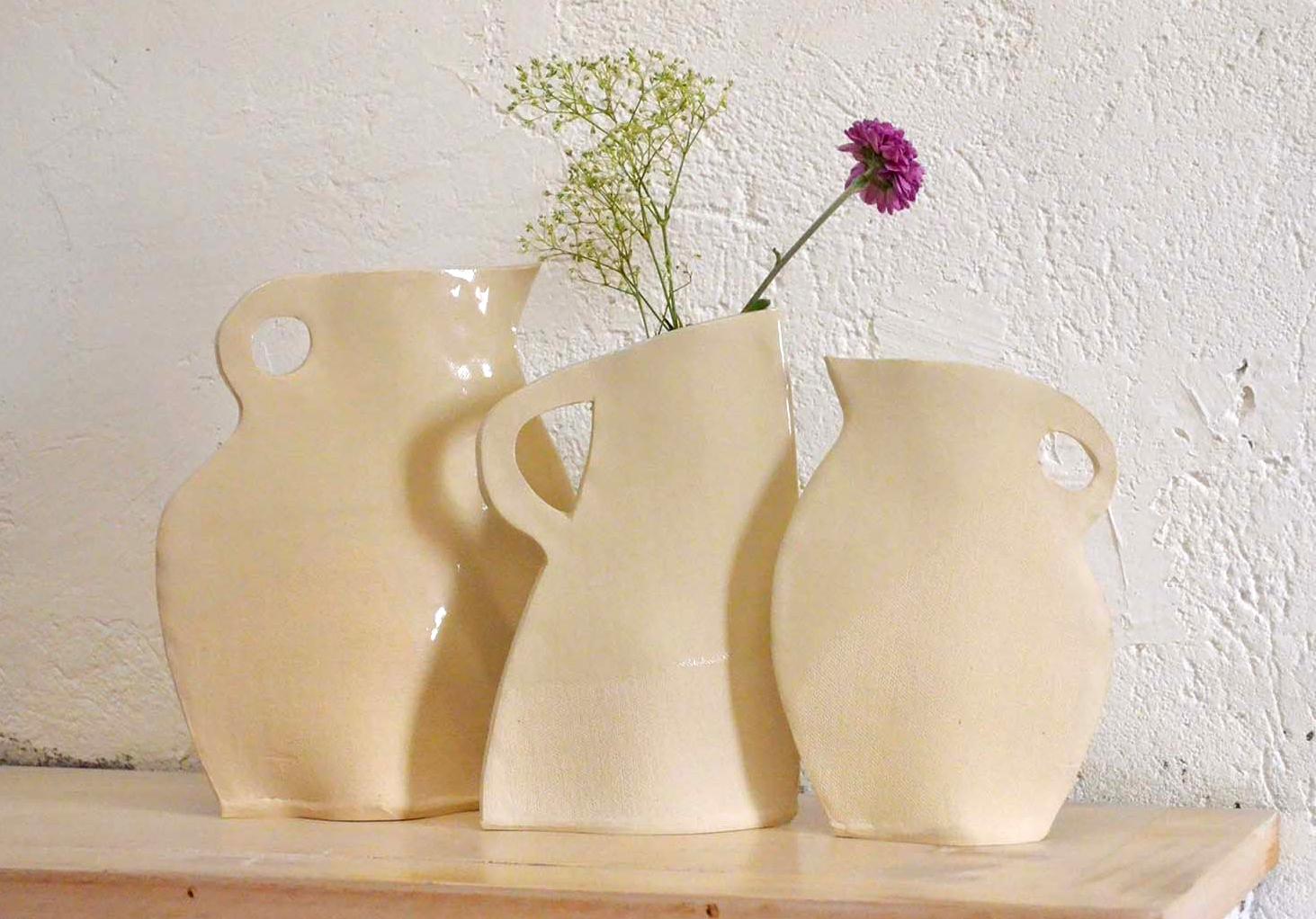 This set of three flat vases by Alison Owen is made through Owen's skillful hand-building technique, utilizing thin slabs of white stoneware clay, partially dipped in clear glaze to create a subtle textural and surface design. The canvas texture of