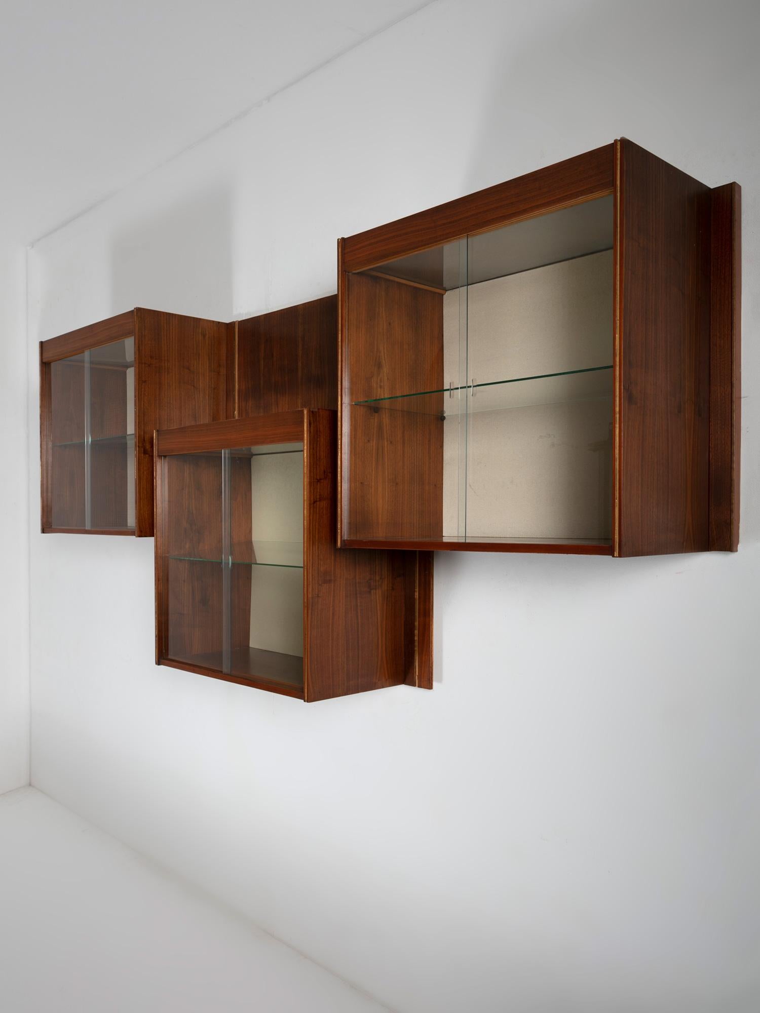 Ensemble de trois vitrines murales avec système d'éclairage et portes coulissantes en verre.
Détails à la feuille d'or sur les cadres en bois.
La pièce provient d'une zone commerciale située sur un bâtiment de Carlo Scarpa.
La taille se réfère à