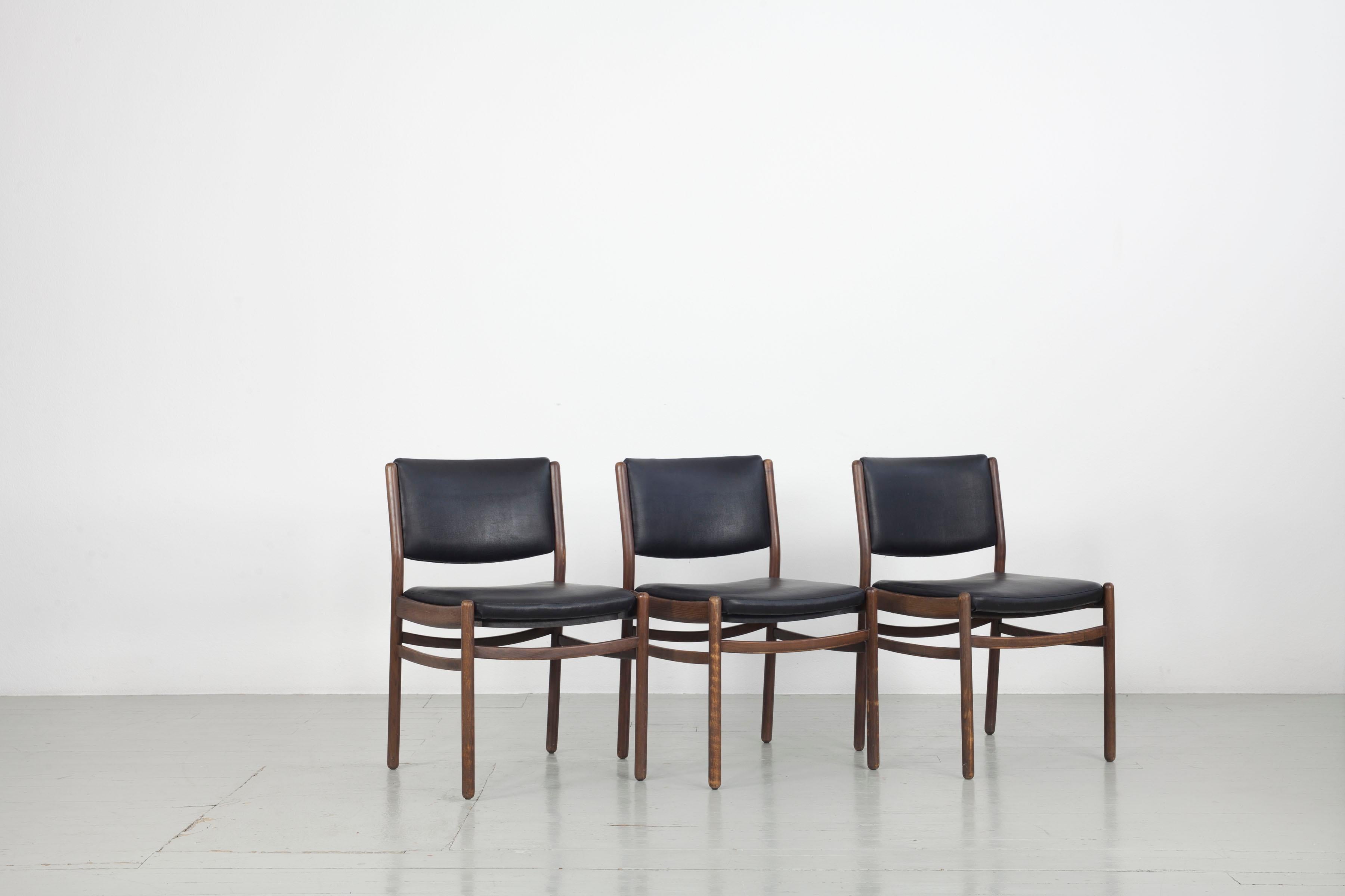 Dieses Set aus drei Holzstühlen wurde in den 1960er Jahren in Italien hergestellt. Der Sitz und die Rückenlehne sind mit schwarzem Kunstleder bezogen und in sehr gutem Zustand. Das Holz ist leicht verblichen und hat Gebrauchsspuren, aber der Sockel