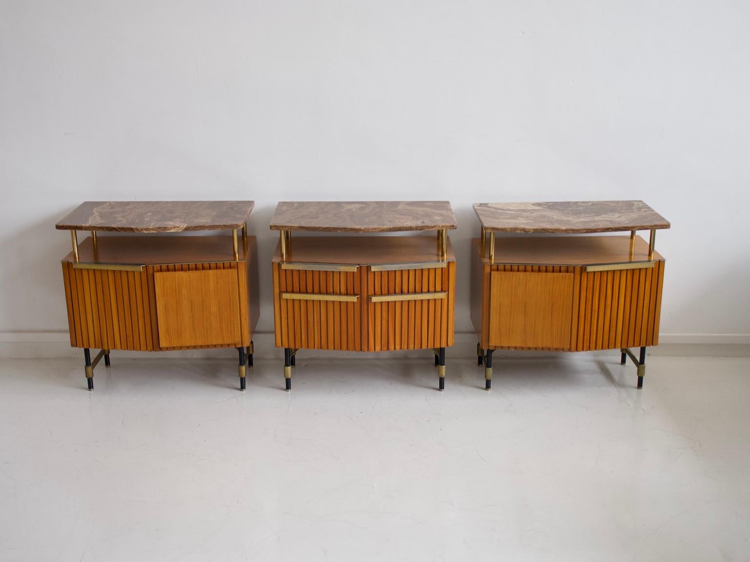 Three sideboard or console tables made in Italy in the 1950s. Featuring wooden structure with brass and lacquered metal details and a marble top. Two credenzas with doors, behind which are shelves and one with two drawers and flap doors.