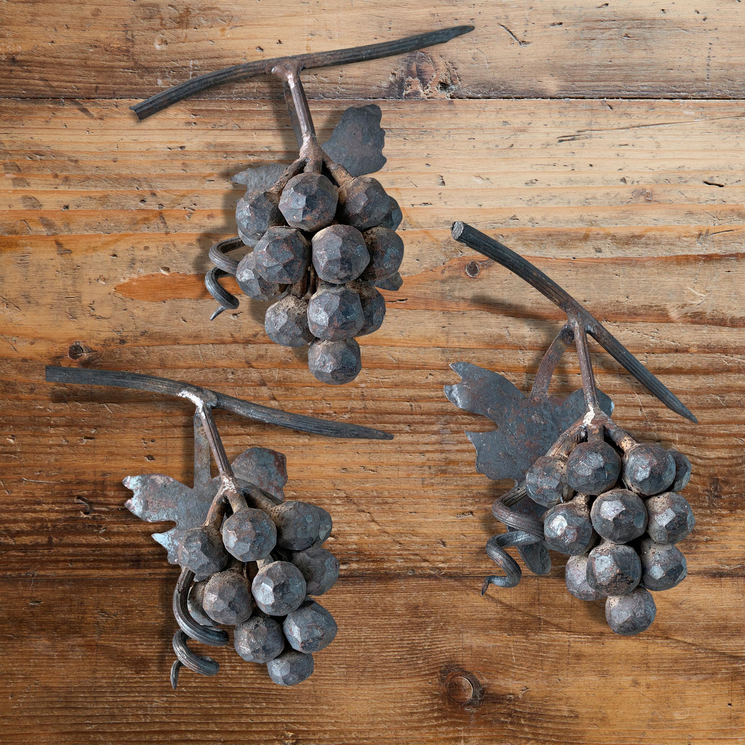 A wonderfully playful set of three hand-wrought and welded iron grape clusters with lifelike leaves, stems, and scrolling vines. Perfect as tabletop decor, or hang them on the wall in your kitchen.