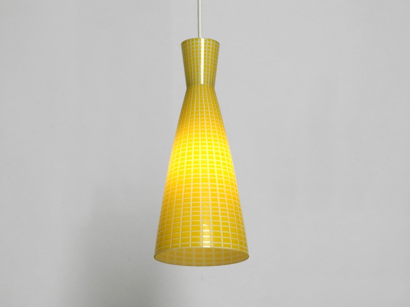 Three very rare yellow midcentury Diabolo glass pendant lamps by Peill & Putzler. Design by Aloys Ferdinand Gangkofner. With rectangular pattern on the shades. Rare and elegant Mid-Century Modern opaline glass pendant lamps. Designed by the famous