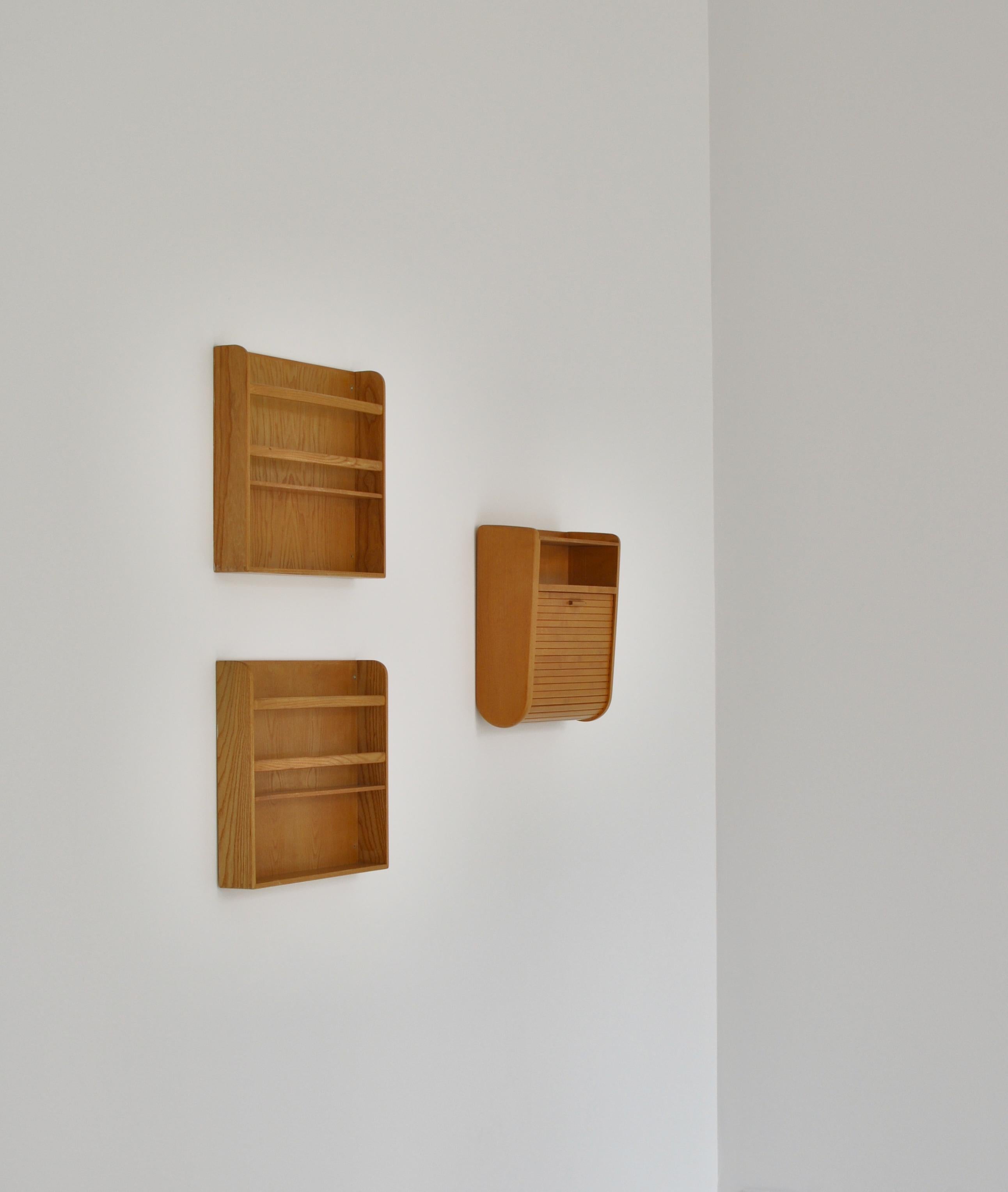 Small wall mounted tambour cabinet of maple and a pair of wall mounted book shelves of elm. Unique. Designed and made approx. 1933–1940 by cabinetmaker Gustav Bertelsen.

Designed and made specifically for Tove & Edvard Kindt-Larsen's summer house