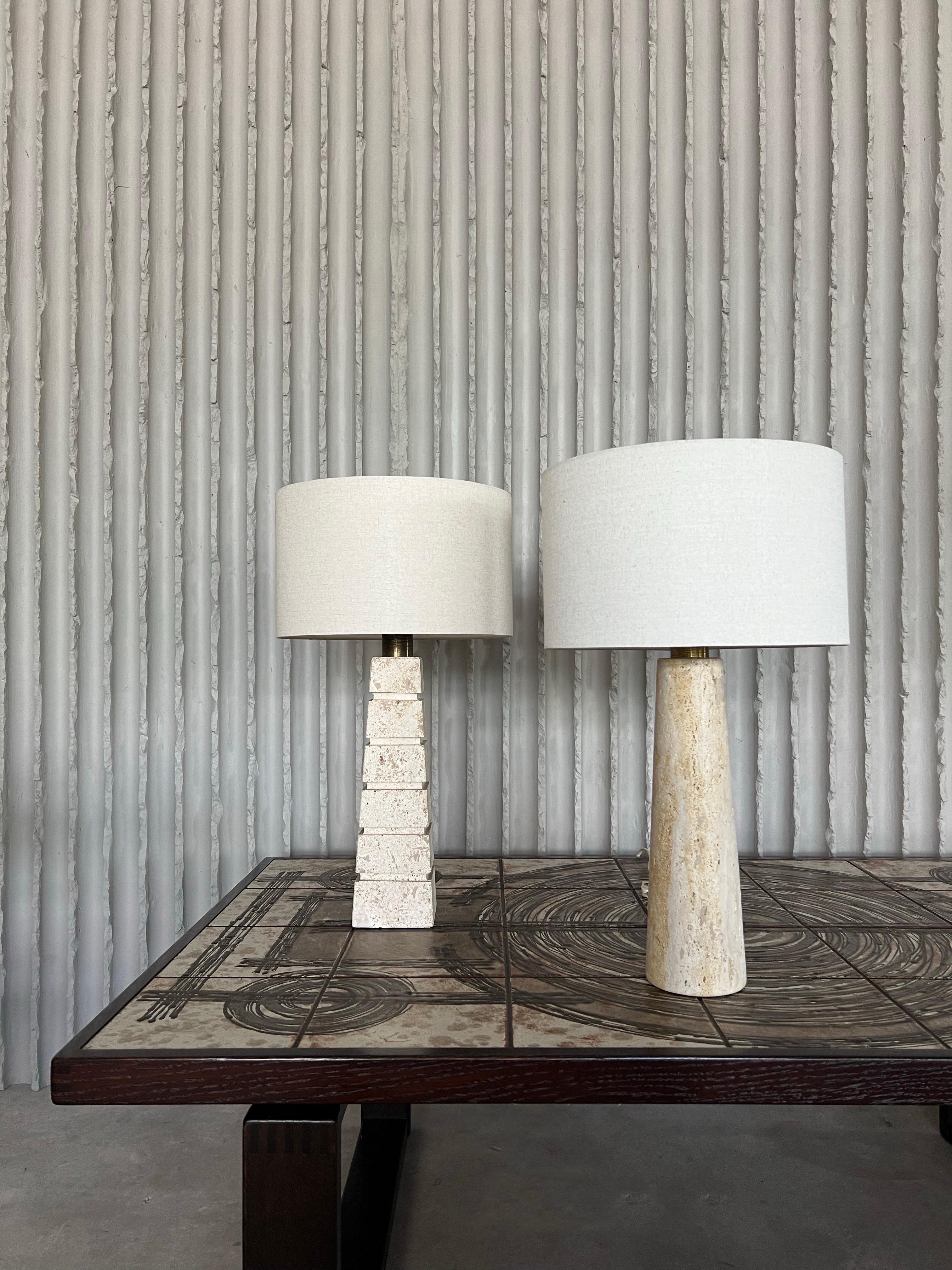 Ensemble de 2 lampes de table travertin avec abat-jour rayé. Les lampes diffèrent par leur forme et leur hauteur, mais elles forment un bel ensemble. Italie, années 1960.
Vous avez le choix entre les teintes de lin rayées ou écrues.
L'une des lampes