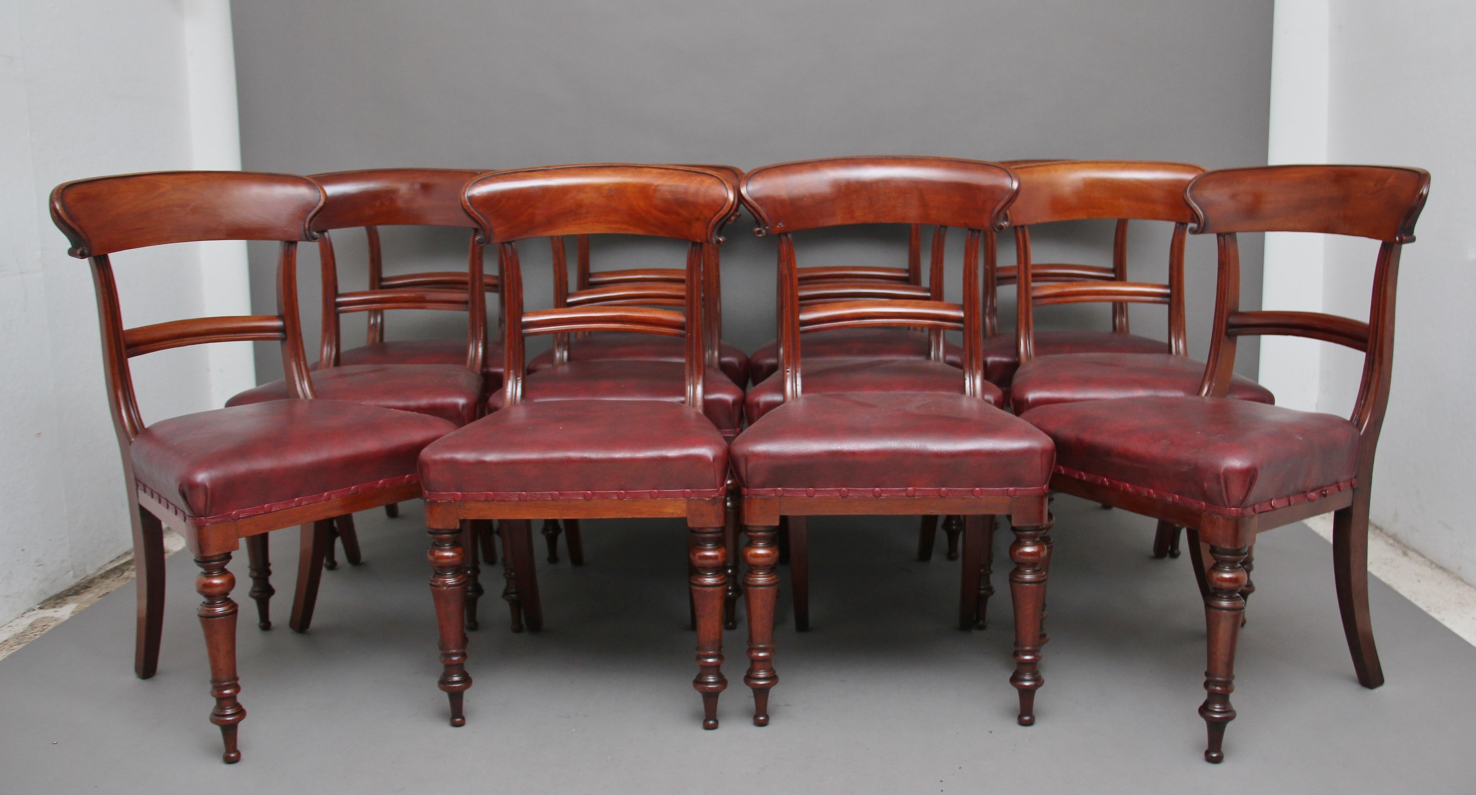 A set of twelve early Victorian mahogany dining chairs, having a curved top and central rail, the top rail having nice carved decoration, maroon stuffover upholstered seat, supported on elegant turned front legs and swept back rear legs. The set are