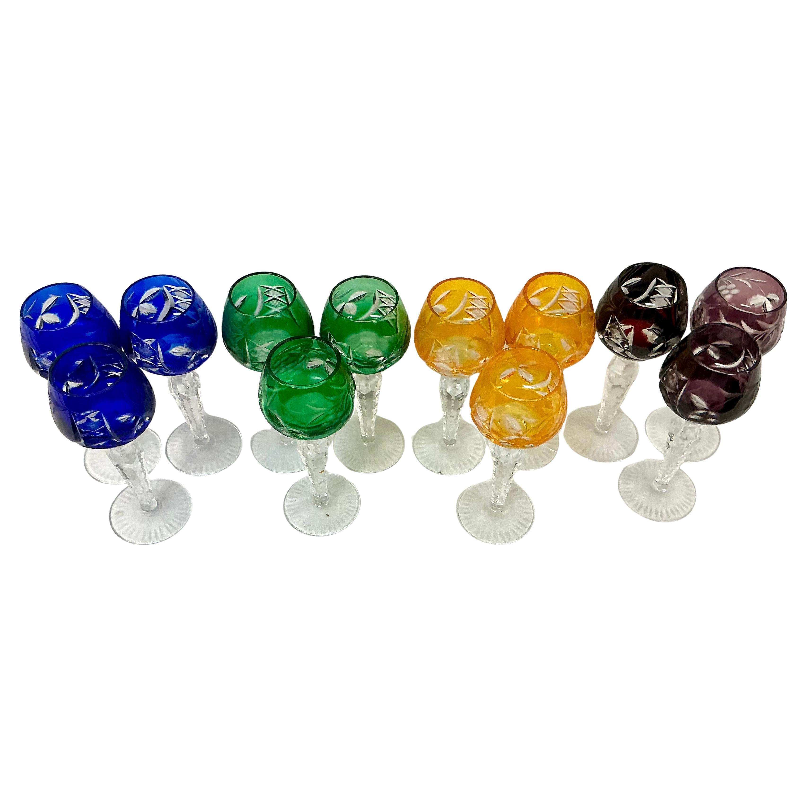 Set of Twelve Hungarian Crystal Cordial Glasses. Glasses come in sets of three, each in its own color scheme, with etched grapes and leaves. The clear crystal stems are notched and the bases have starburst motif. The color schemes are Cobalt