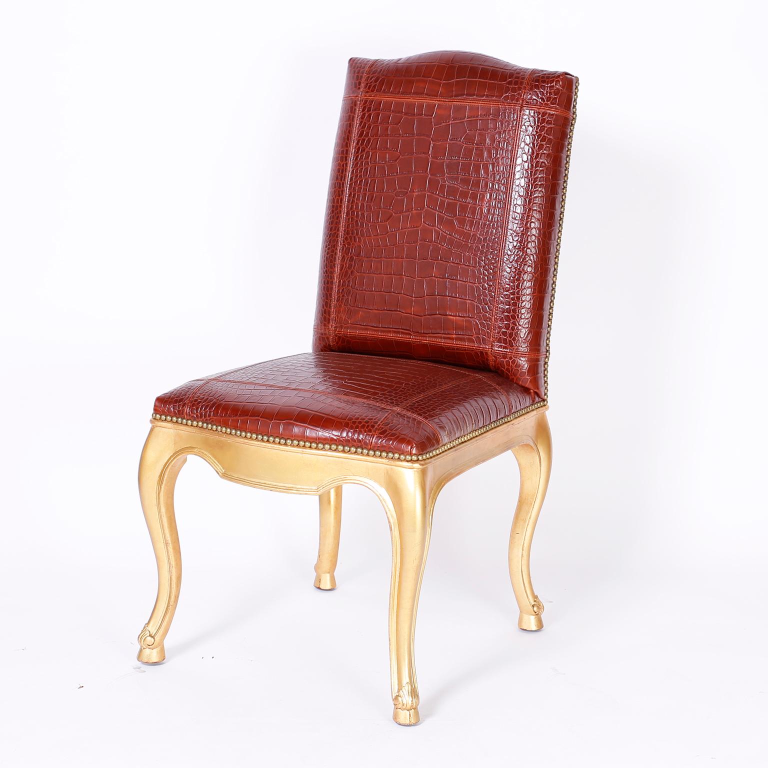 Stand out set of twelve dining chairs with oxblood faux alligator tooled leather upholstery bordered in brass tacks over gold cabriole legs with acanthus leaves and hoof feet. Signed Ralph Lauren.